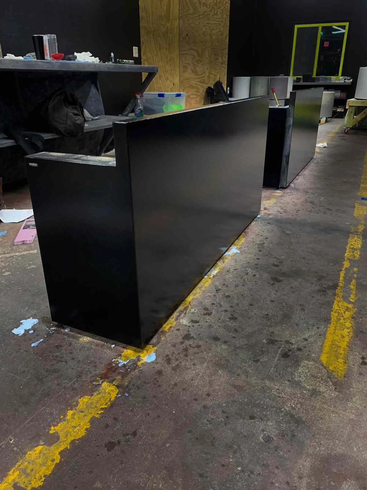Shop view of custom turnkey concrete desk components with monolithic black finish, fabricated by The Concrete Anomaly prior to installation.