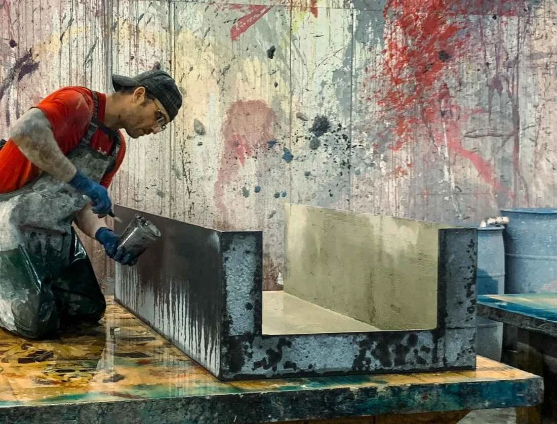 Artist finishing a large custom concrete element by hand in the studio during surface treatment.