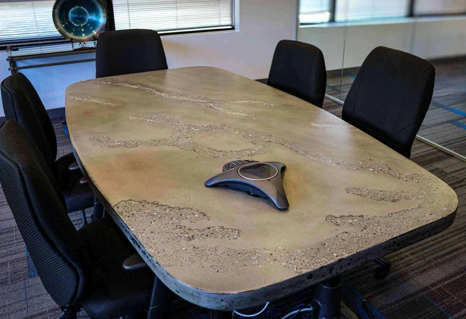 Custom concrete executive conference table with integrated power and speaker access, fabricated by The Concrete Anomaly for Structural Group headquarters.
