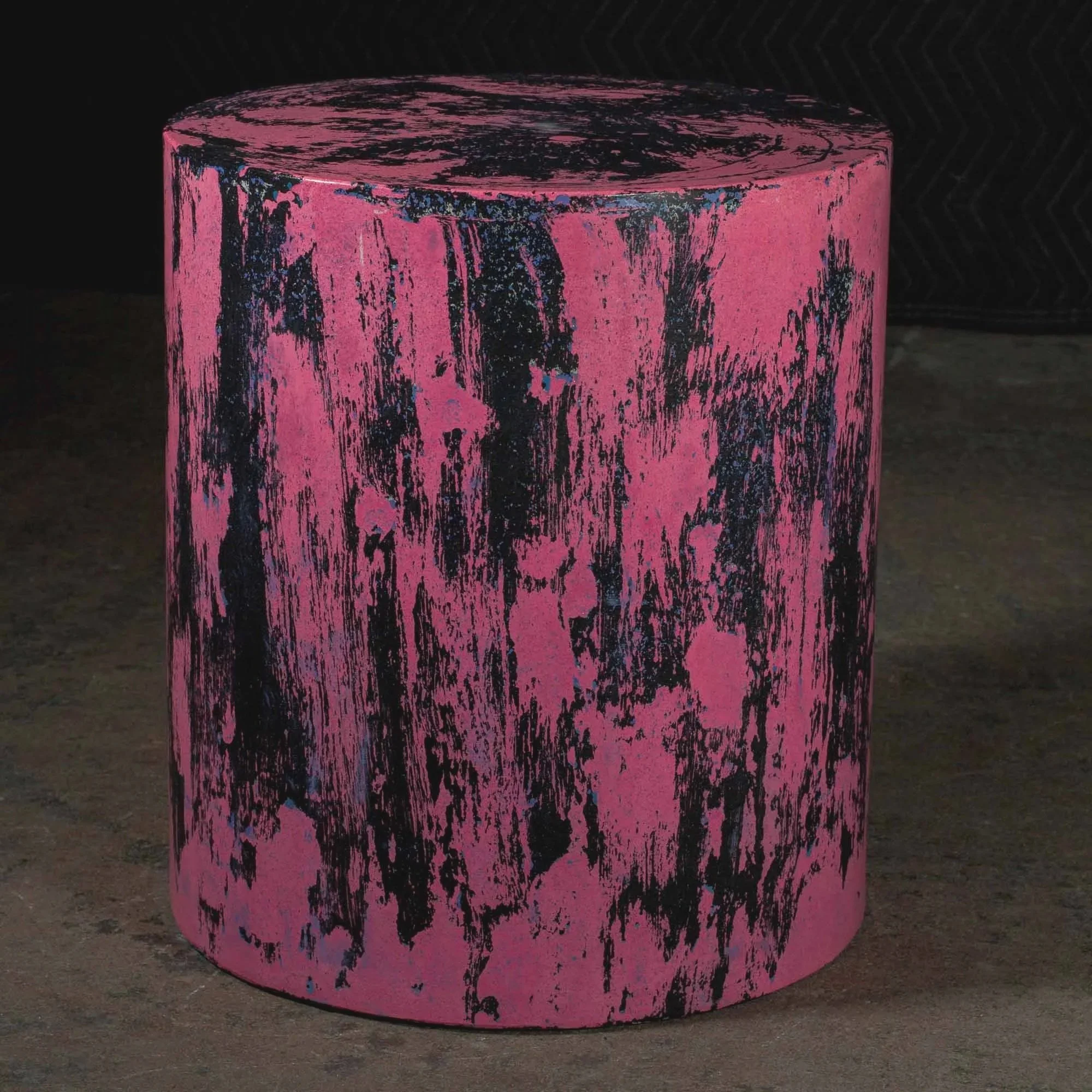 Sculptural concrete pedestal with aggressive black distressed patterning over vivid pink mineral surface inspired by controlled material decay.