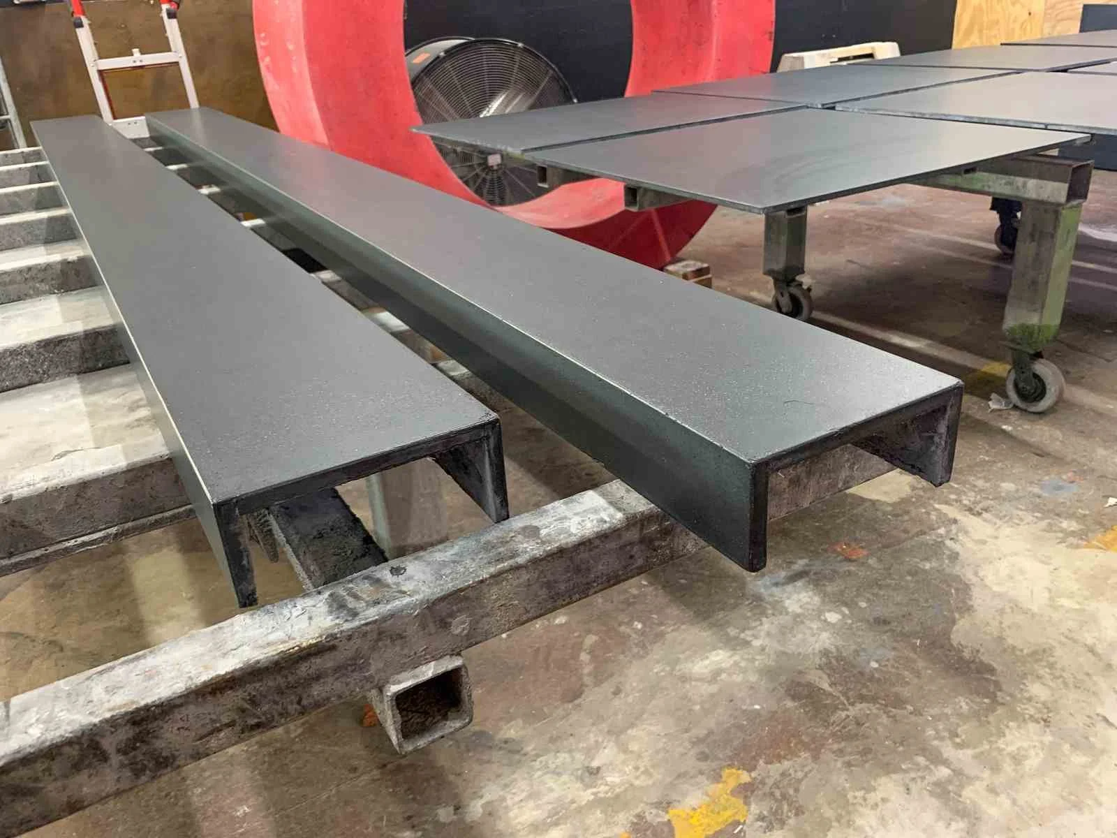 Concrete end wall caps fabricated as linear architectural elements, staged in the workshop during finishing.