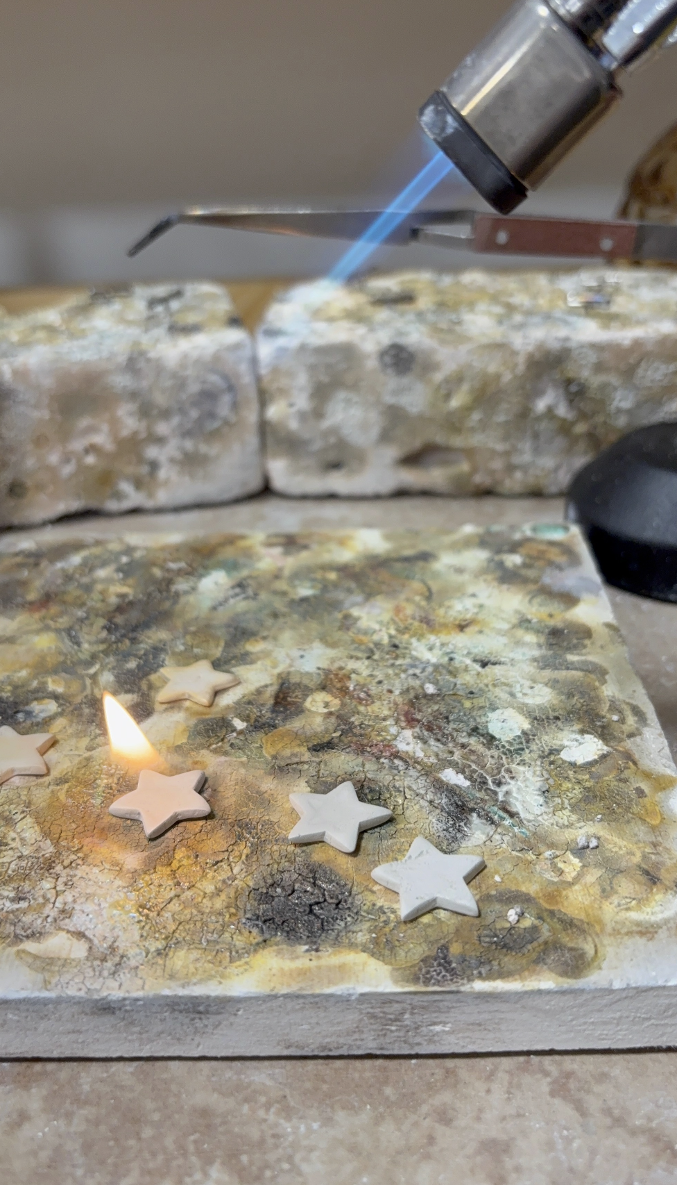 Picture of silver clay stars on a soldering block being torched
