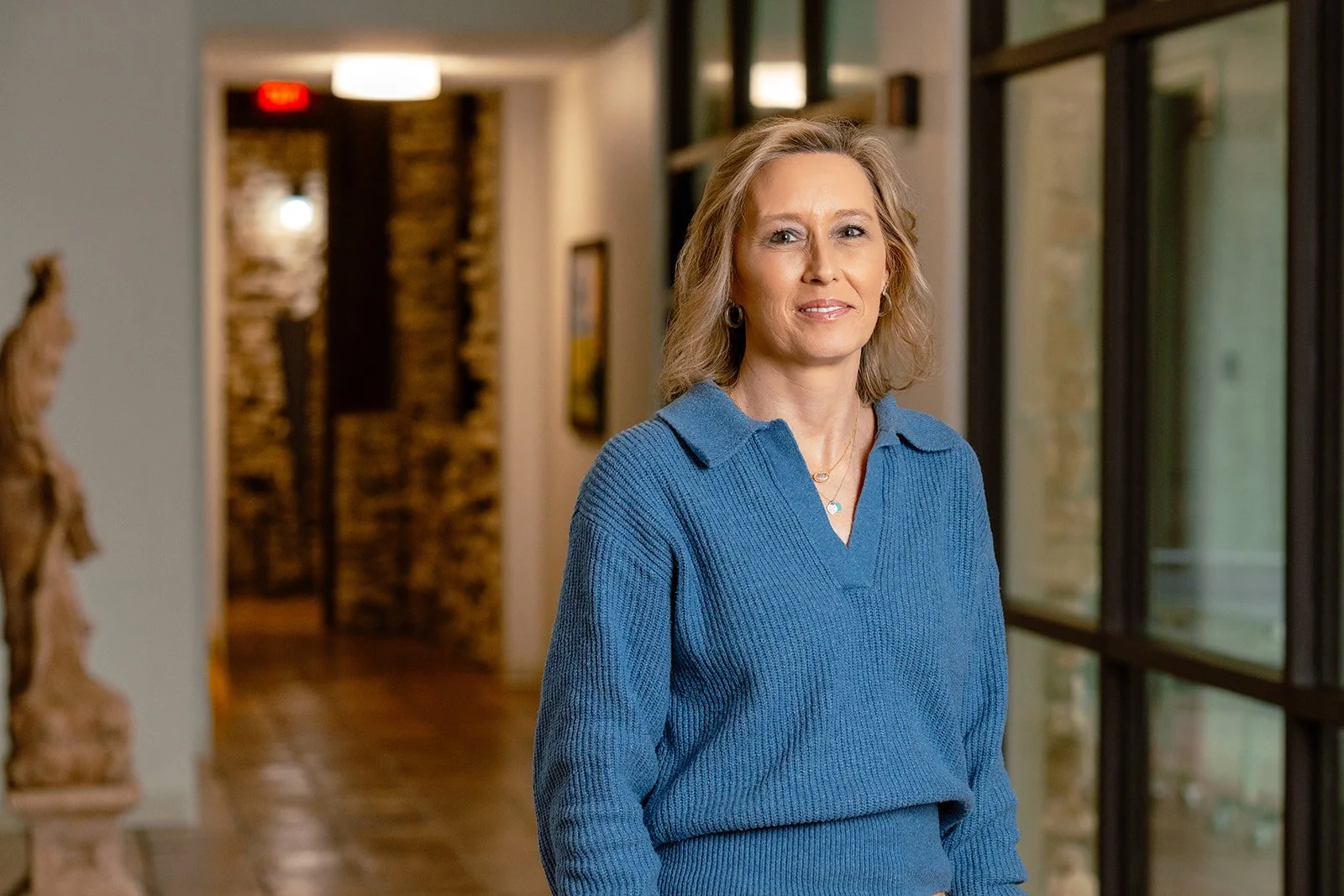 A woman in a blue sweater standing in a corridor