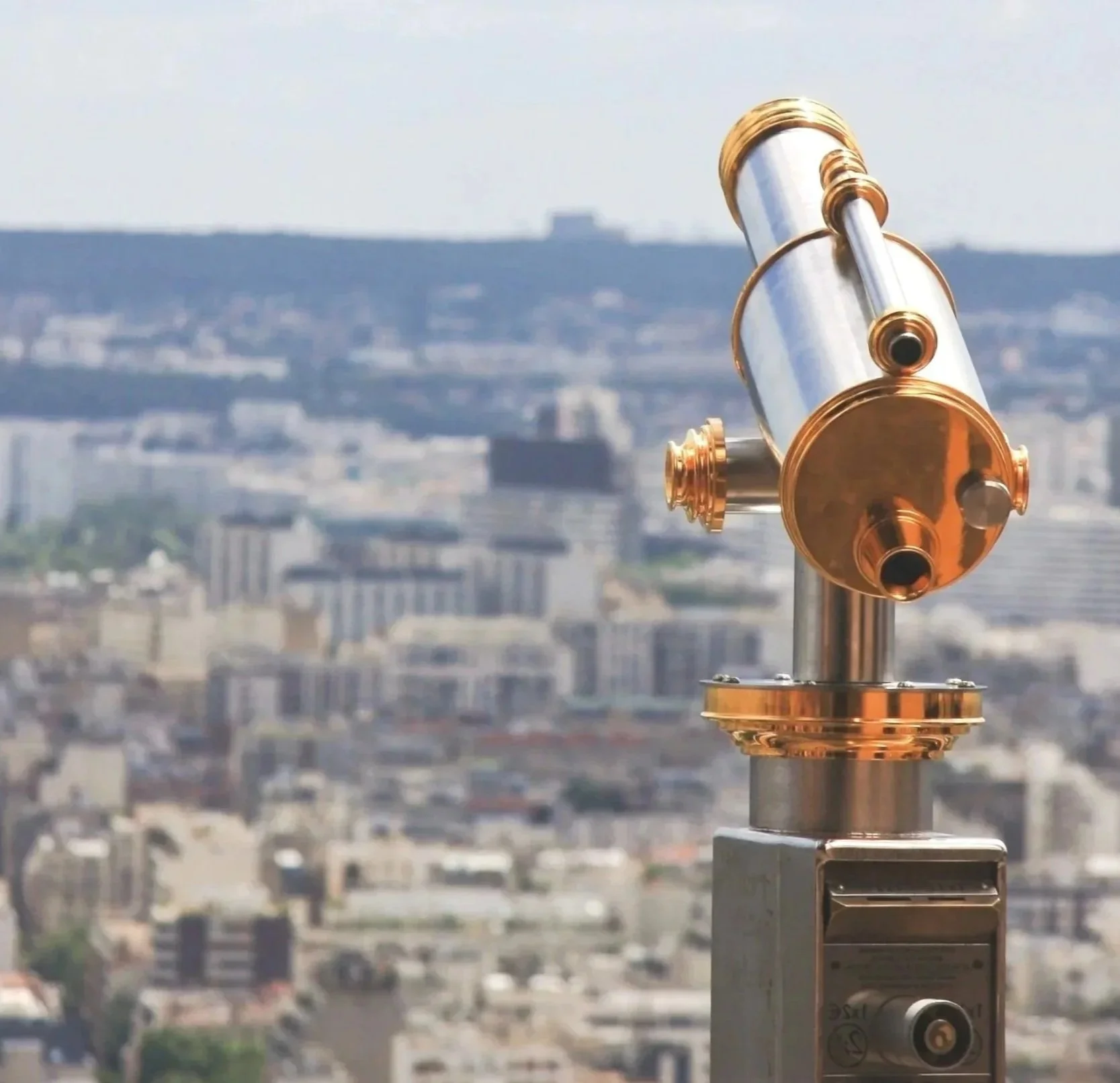 A telescope mounted on a stand with a cityscape in the background.
