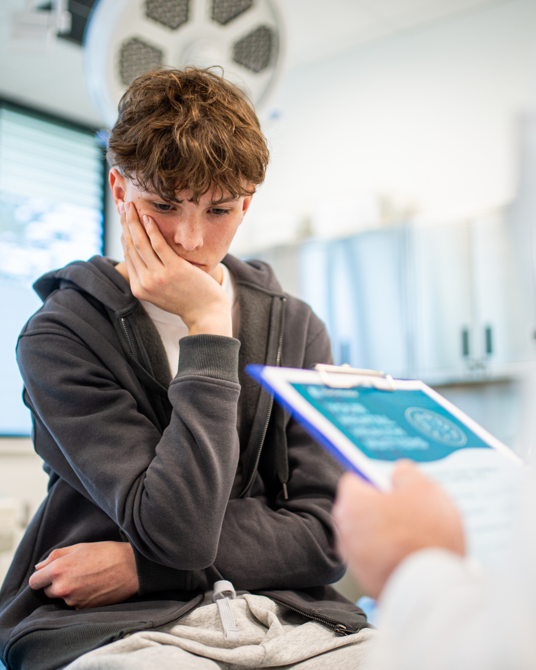 Concerned teenage boy consulting doctor during medical appointment. Adolescent mental health and healthcare support concept