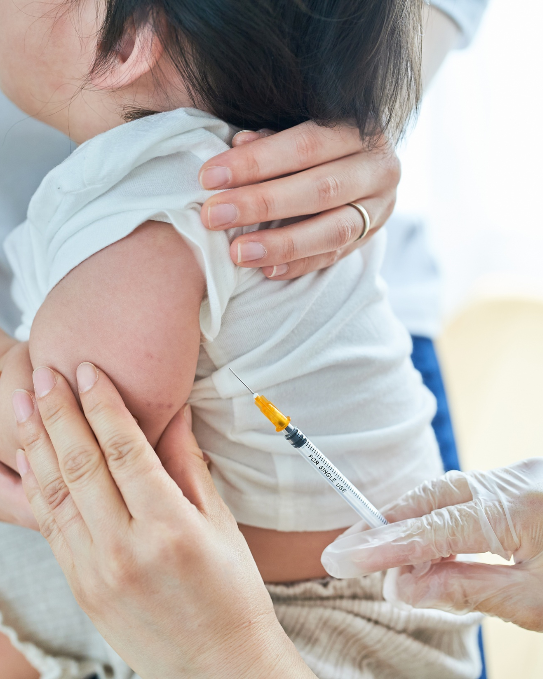 Pediatric nurse giving vaccine injection to baby’s arm during immunization appointment. Child receiving vaccination shot for disease prevention and healthcare protection.