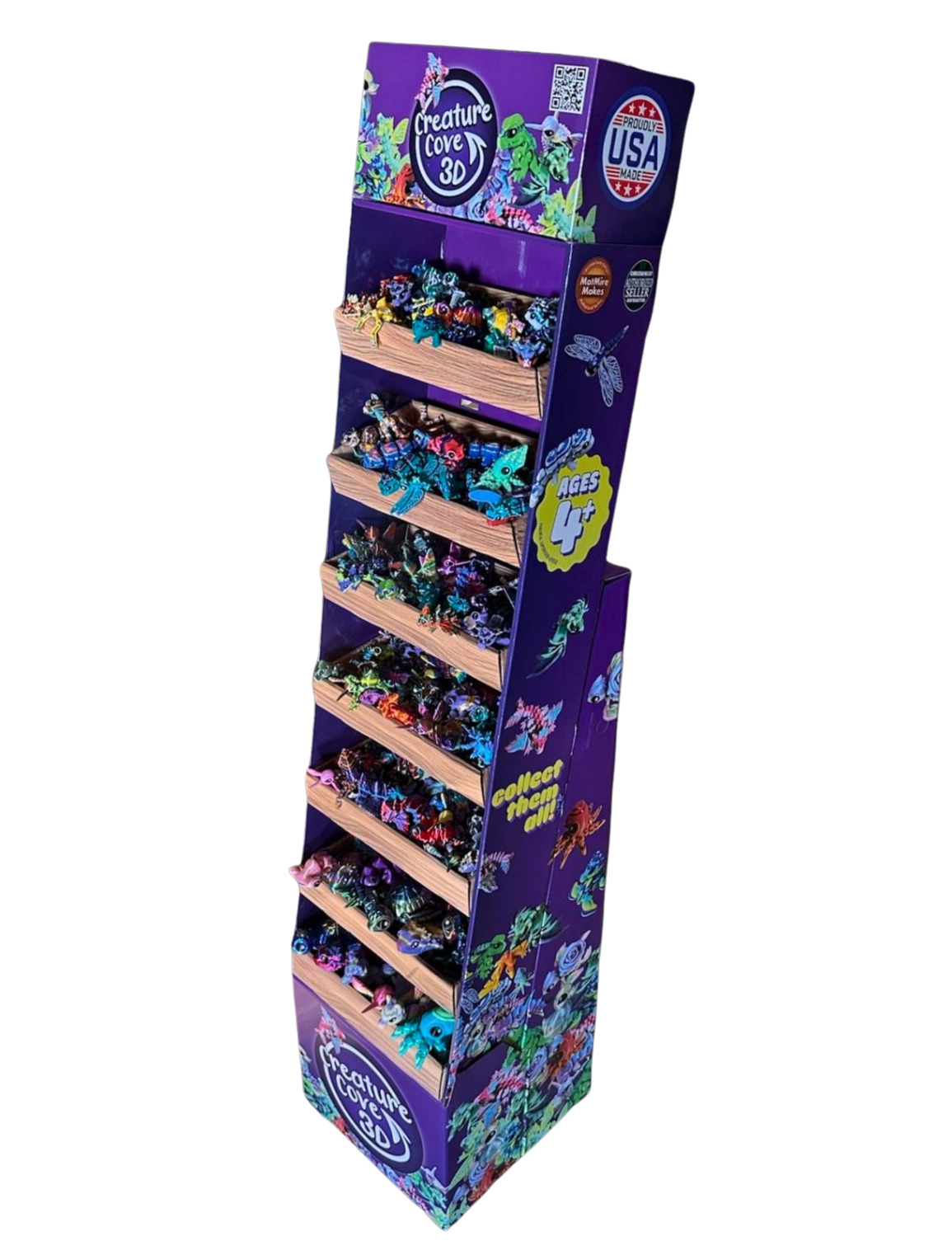 A colorful floor shipper display stand for Creature Cove 3D toys, featuring various creatures on multiple shelves, with purple, blue, and green theme, age 4+ indication, and patriotic USA logos.