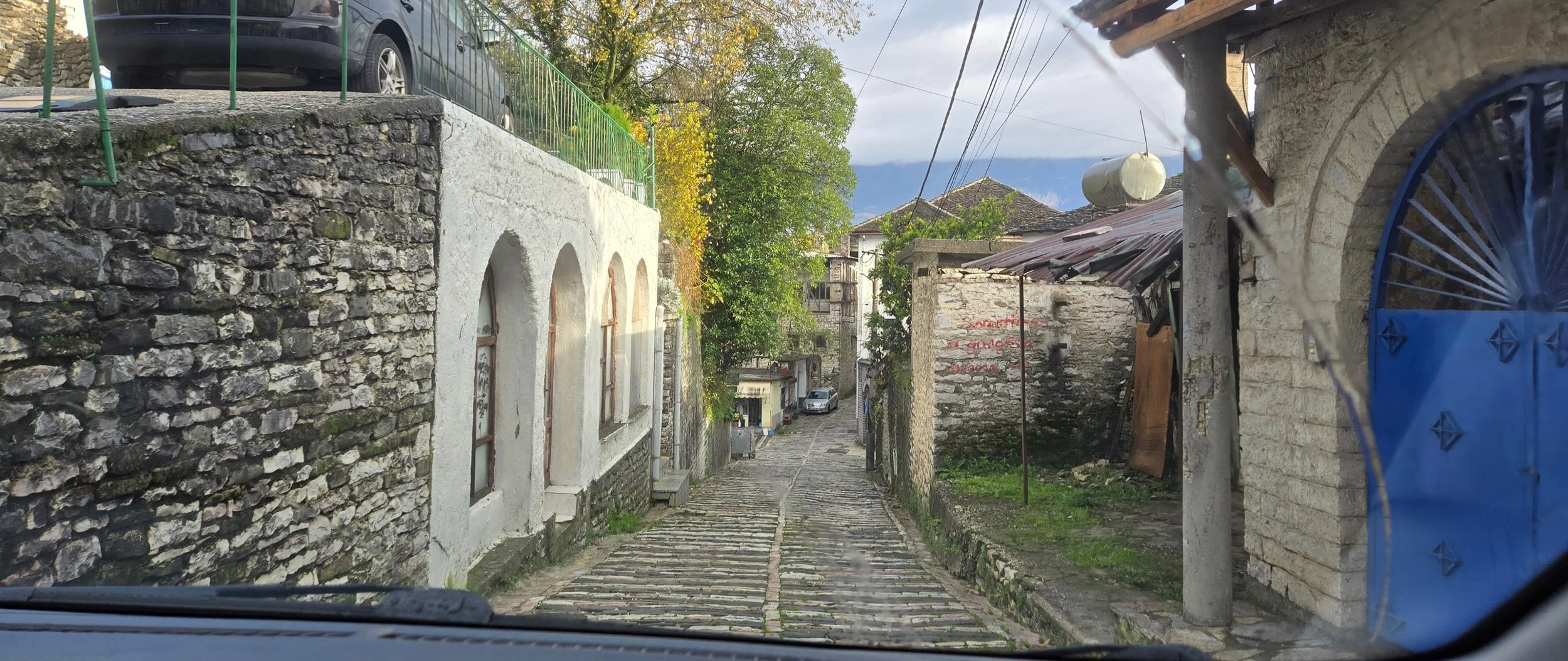 driving down the hotel road in Gjirokaster Albania Stone street, very narrow parking both sides and two way traffic