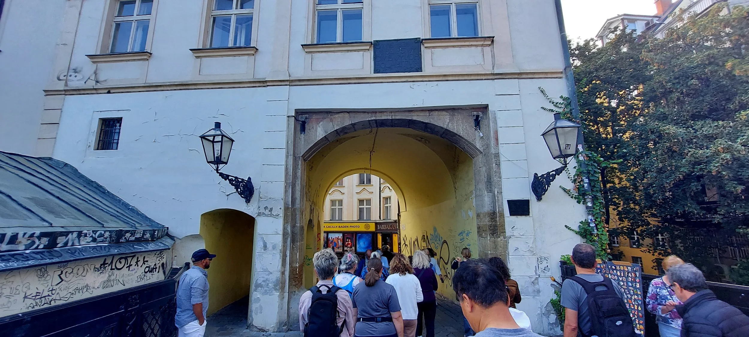 view of a tour group in Bratislava, Slovakia walking through an old gateway now built with houses over it