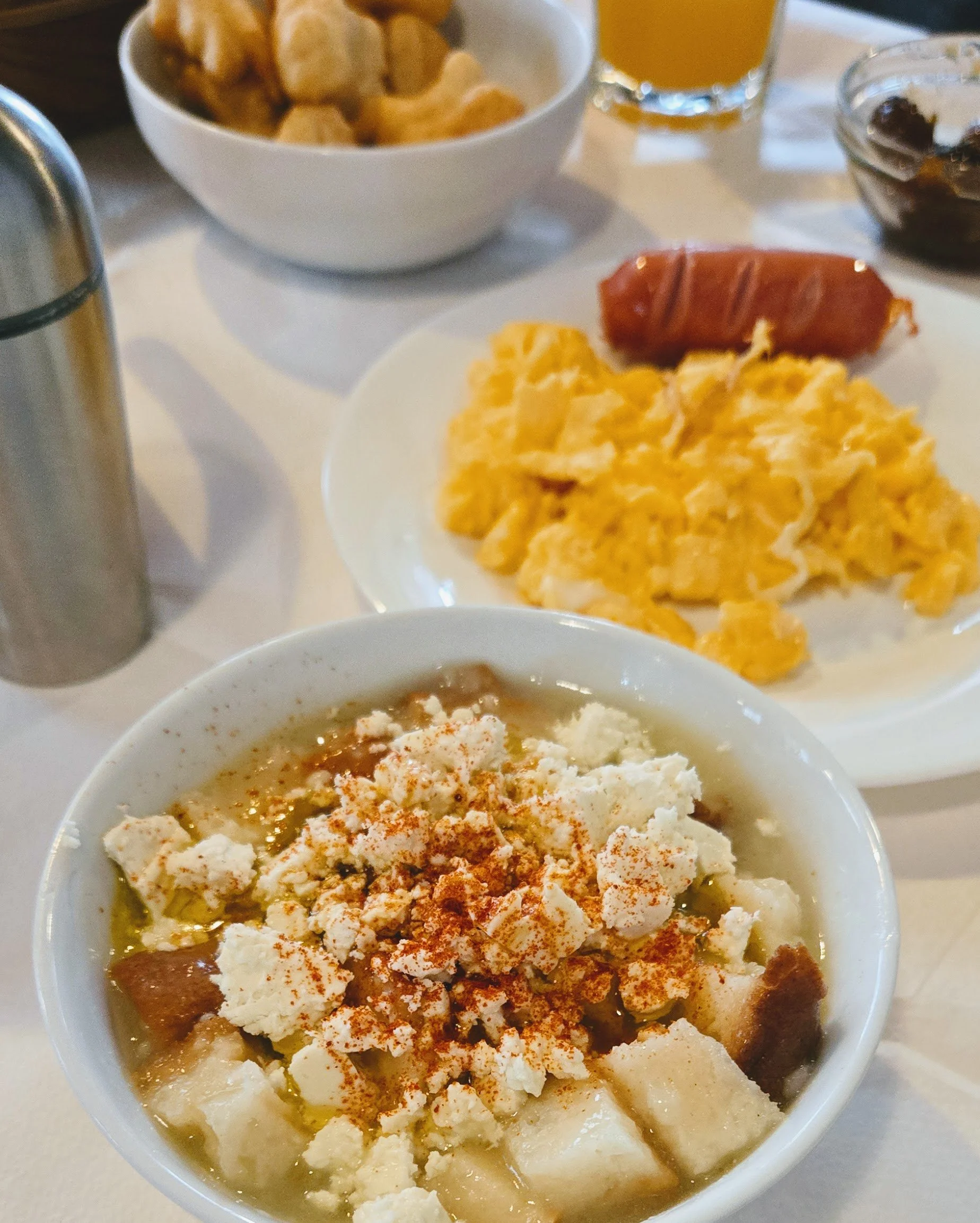 local breakfast items in Gjirokaster Albania, eggs, sausage,  local pancakes puffs, Oj. coffee and a bowl of homemade traditional bread porridge