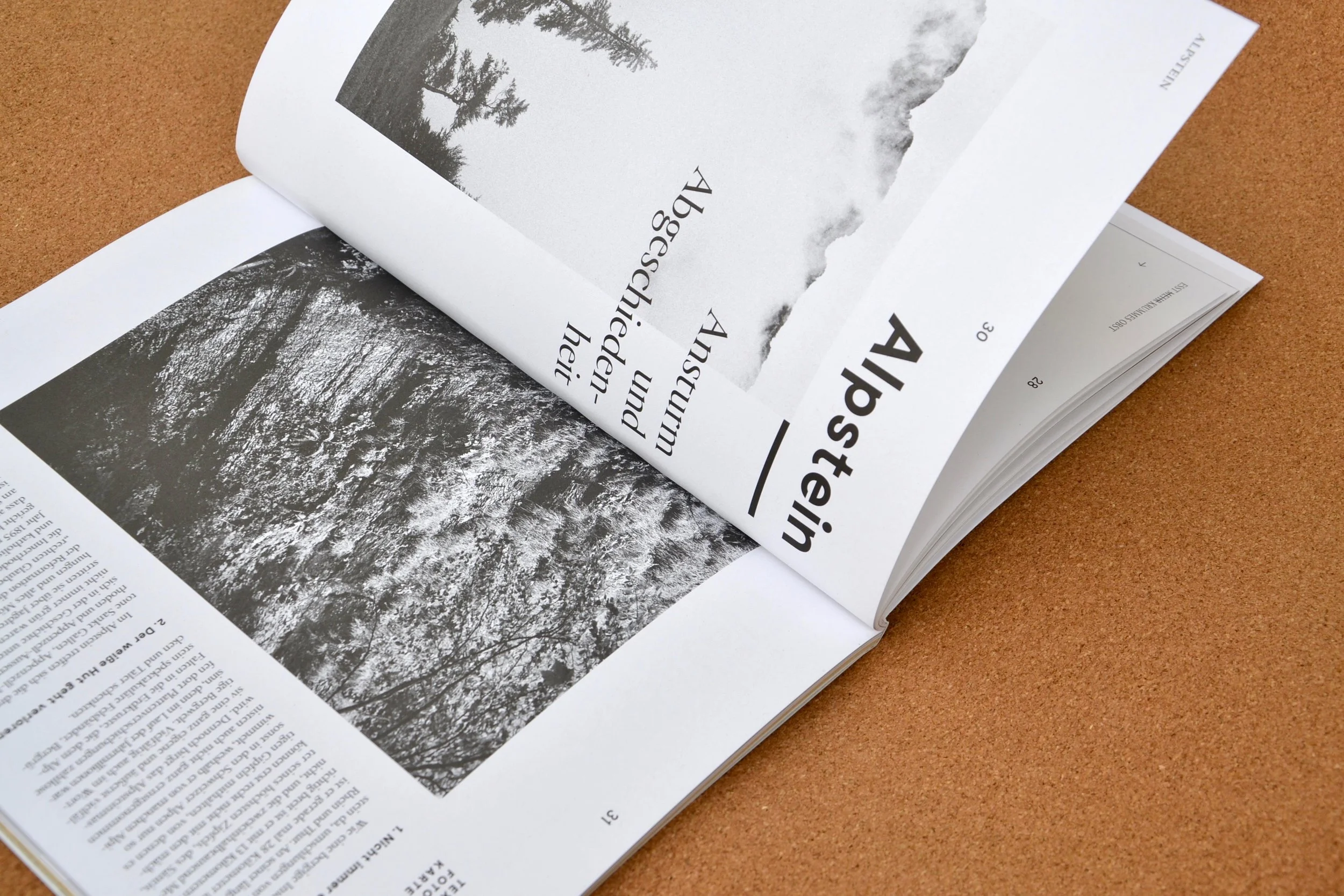 Offen geblättertes Magazin mit Schwarz-Weiß-Fotografien und Text auf einer braunen Oberfläche.
