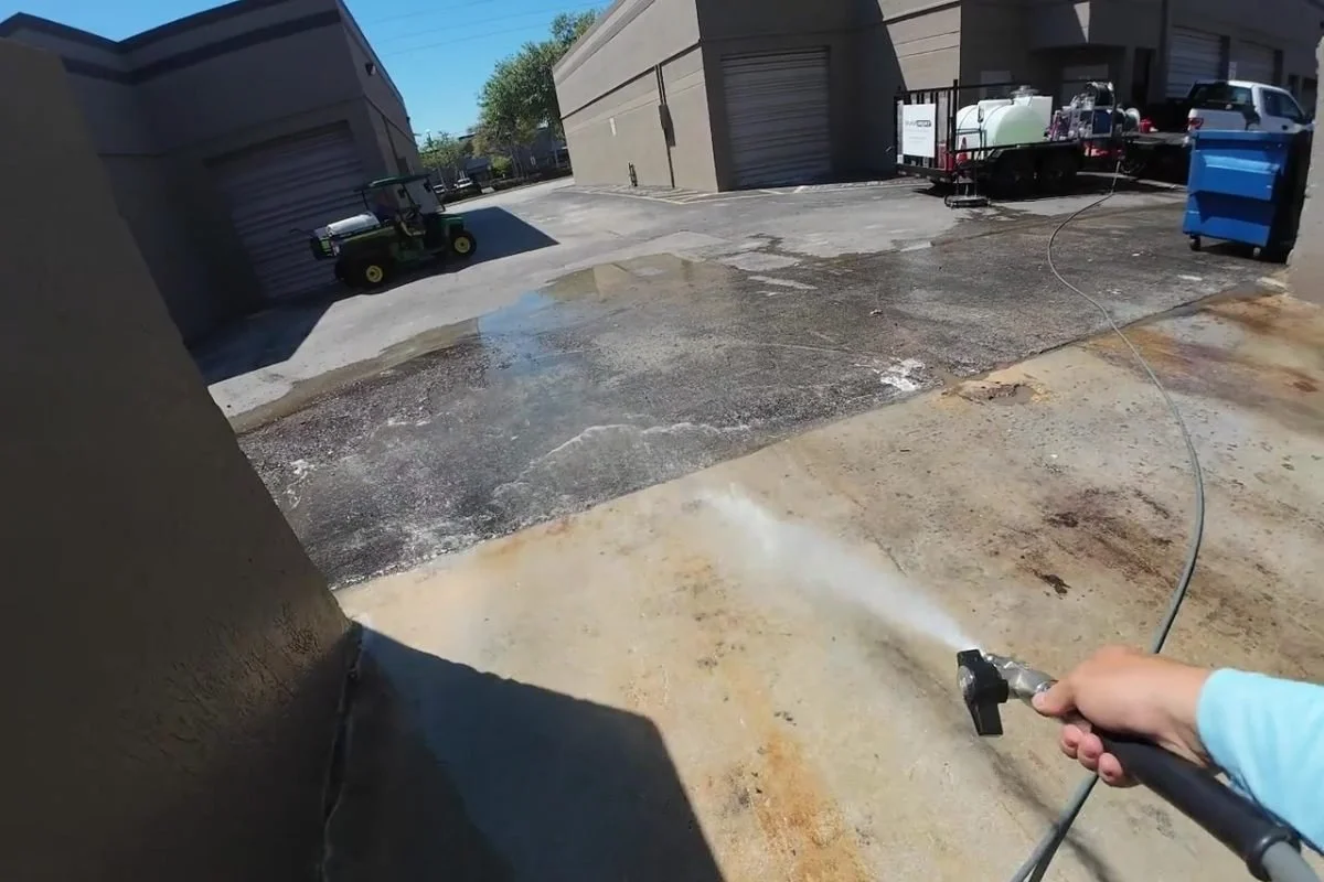 Cleaned dumpster pad area in a commercial property showing improved hygiene and surface condition.