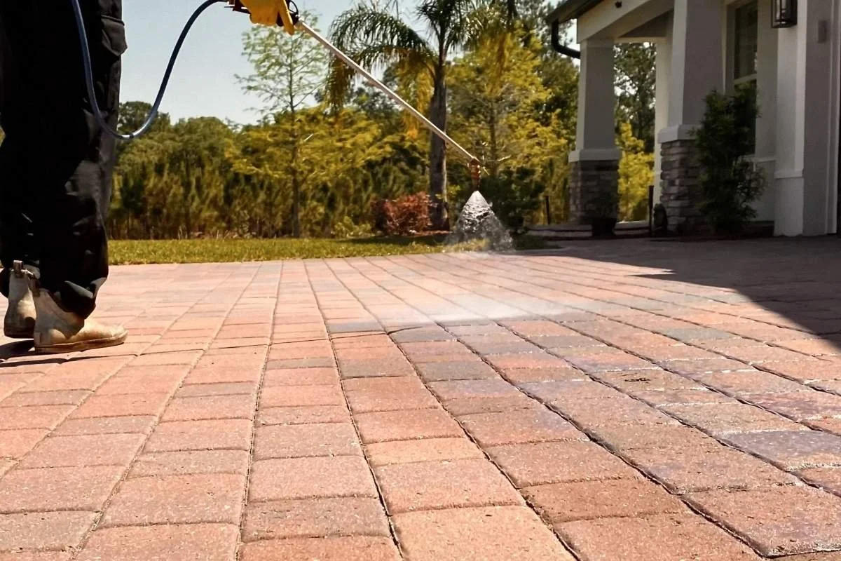 BravaSurface technician applying sealer on brick-paver driveway in Broward County, demonstrating professional surface protection process.