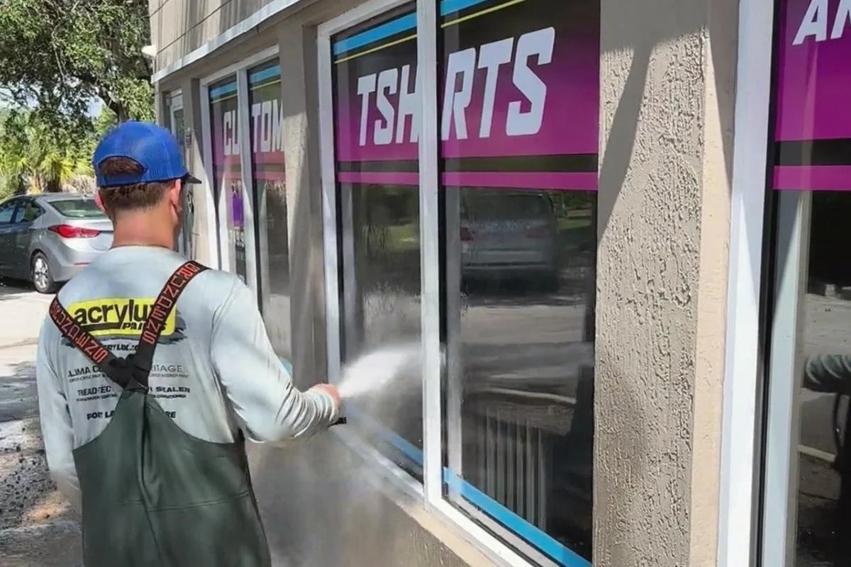 Technician cleaning the exterior glass windows of a commercial storefront in Sunrise, Florida.