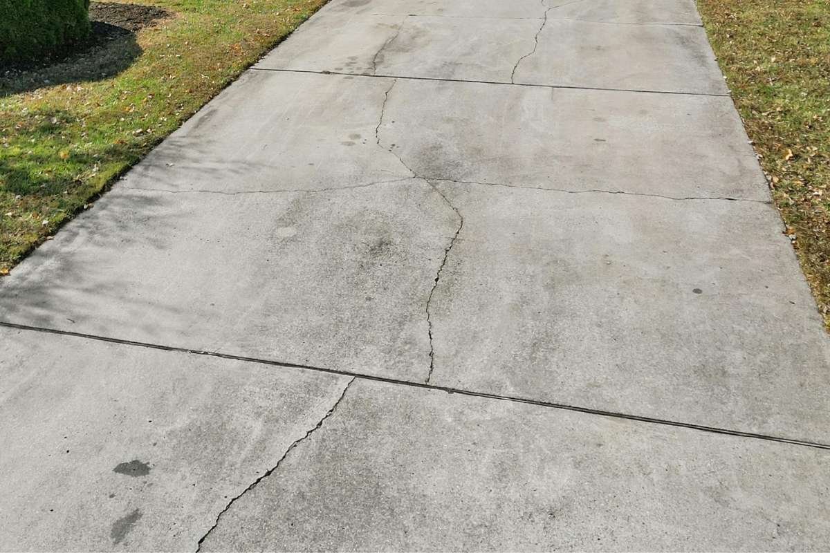 Oil stains on a concrete driveway showing dark vehicle fluid marks before cleaning.