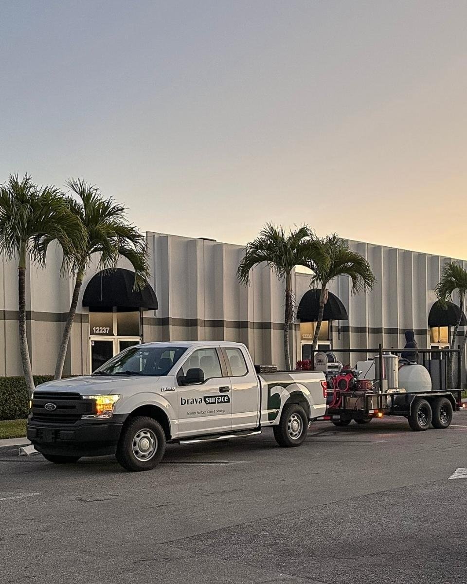 BravaSurface service truck and equipment trailer at a South Florida commercial property near sunset.