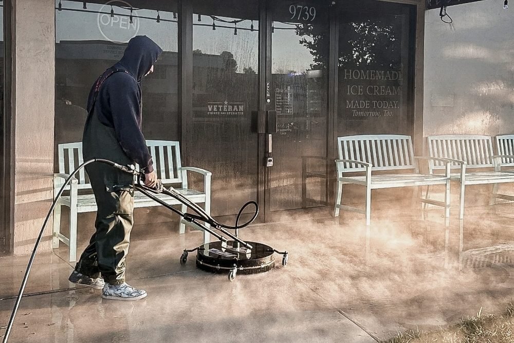 Pressure washing exterior concrete surface with professional surface cleaning equipment.