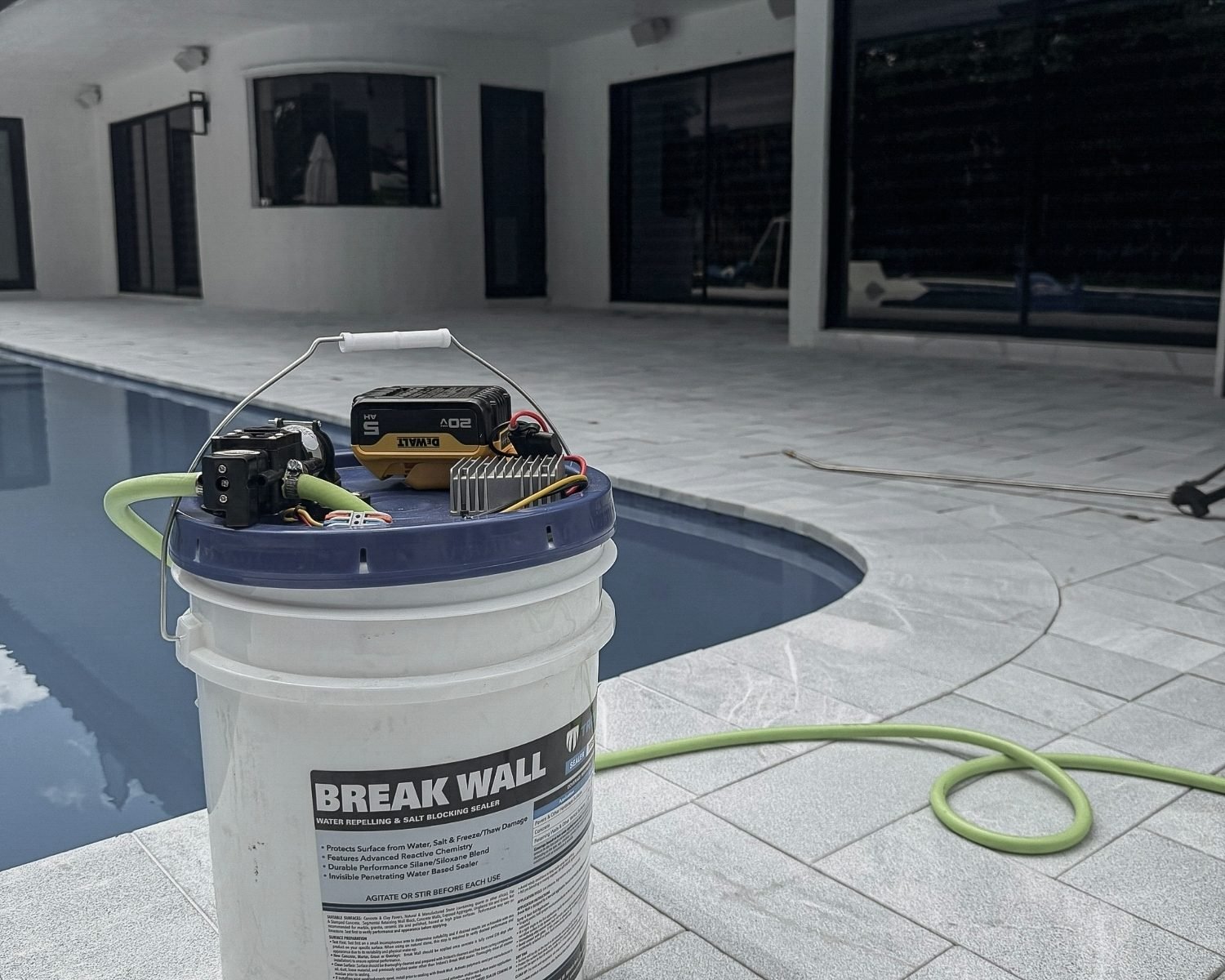 Natural stone pool deck sealing process with professional sealer preparation near a residential pool area.