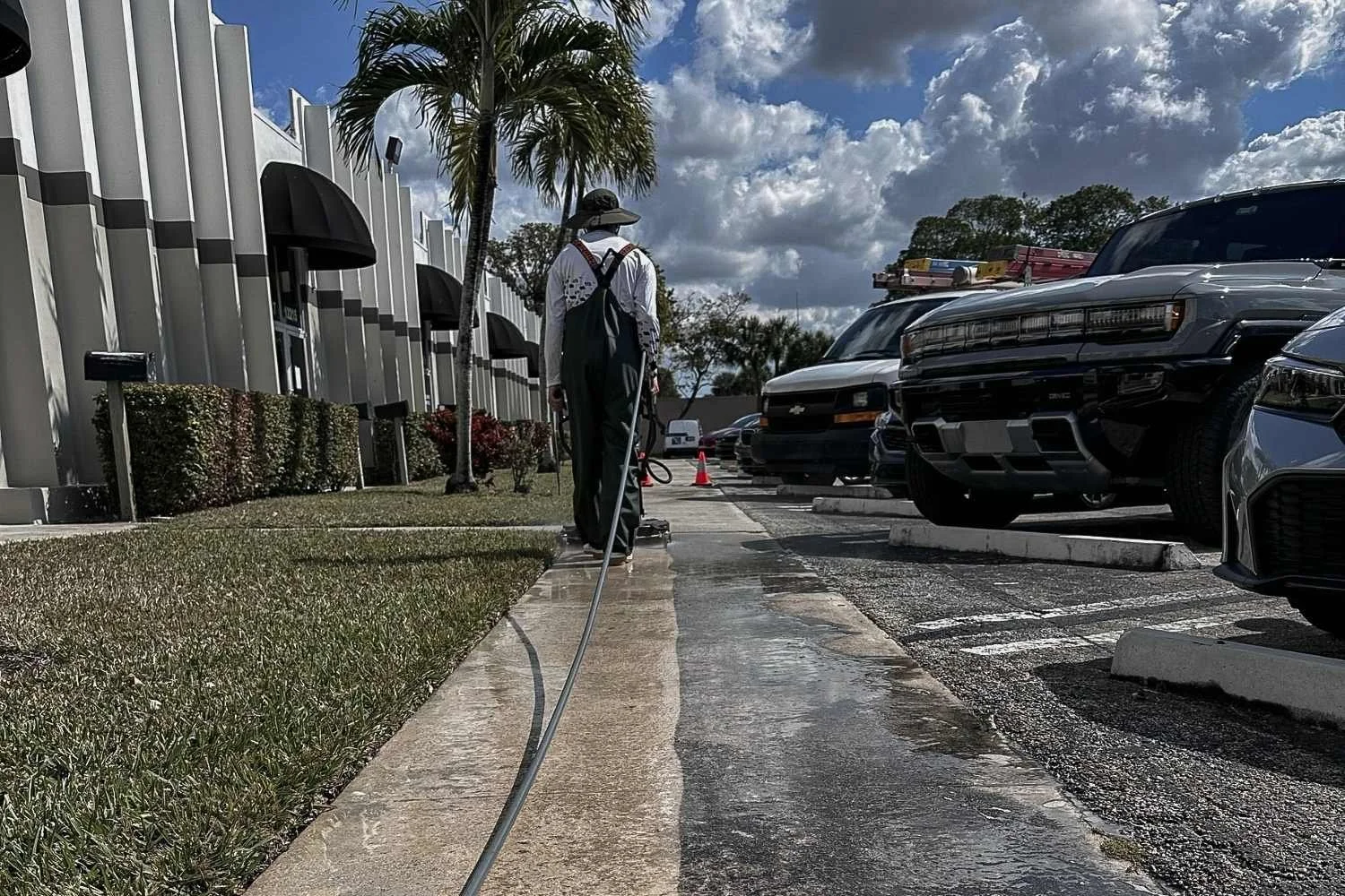 Commercial sidewalk cleaning outside a Broward County property with parked cars, storefronts, and high-traffic walkways.