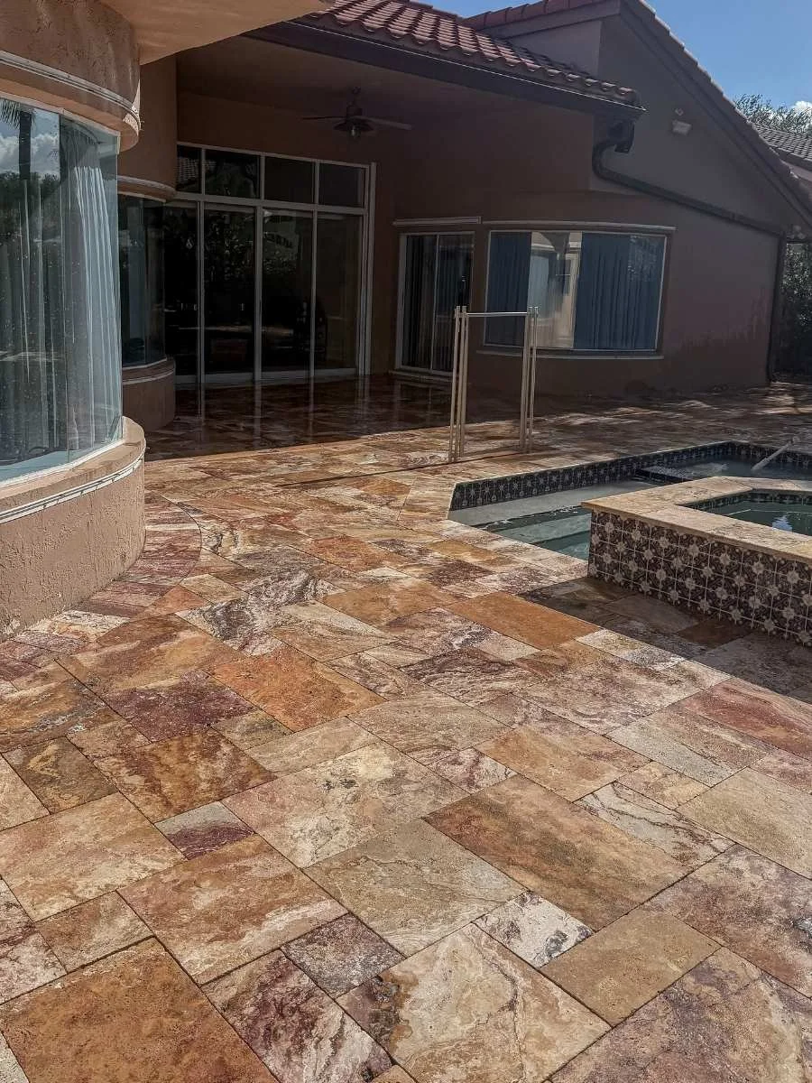 Travertine pool deck after cleaning, joint preparation, and sealing at a Coral Springs residential property.