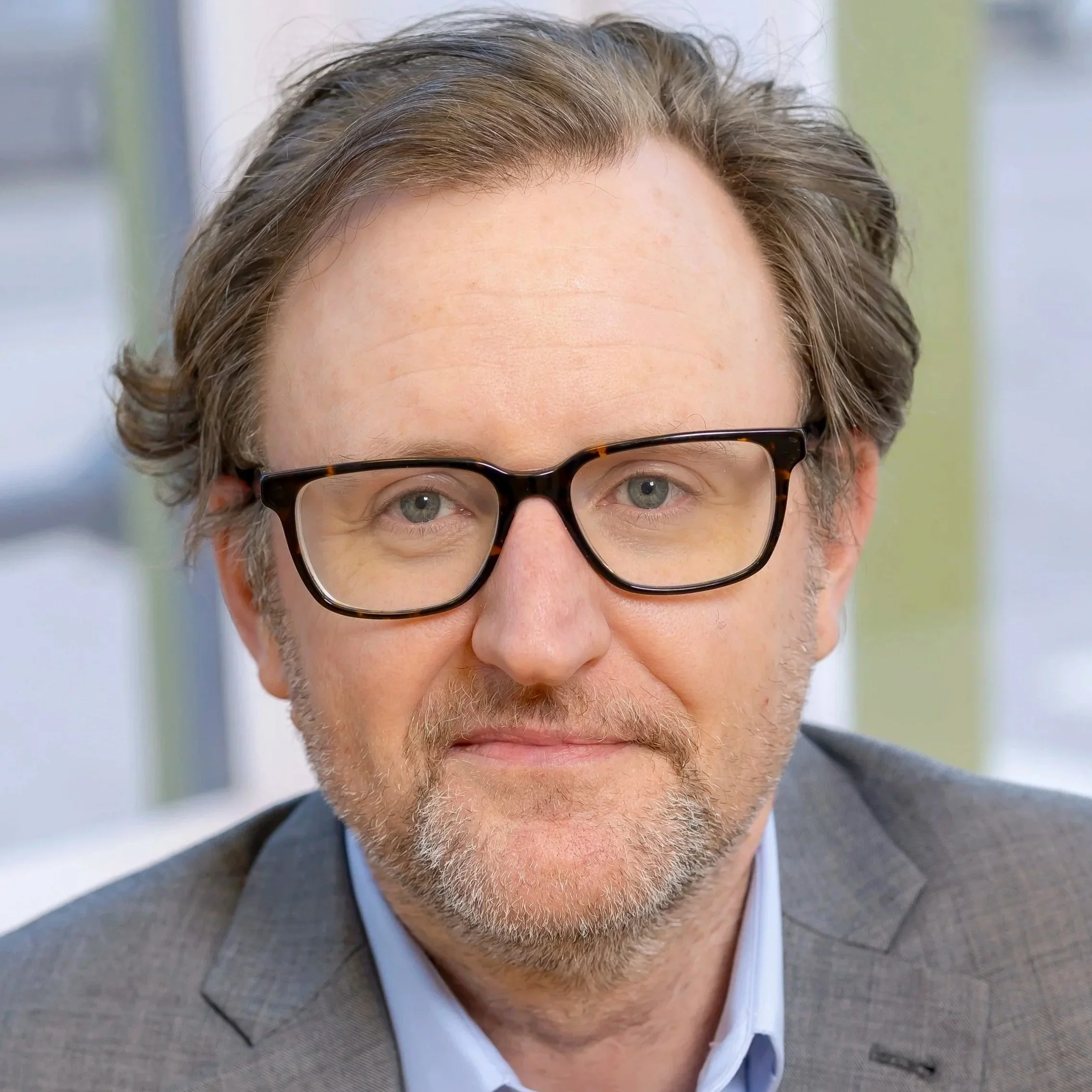 A man with glasses and a beanie taking a selfie with a French Bulldog in front of him, both looking directly at the camera. The image is in black and white.
