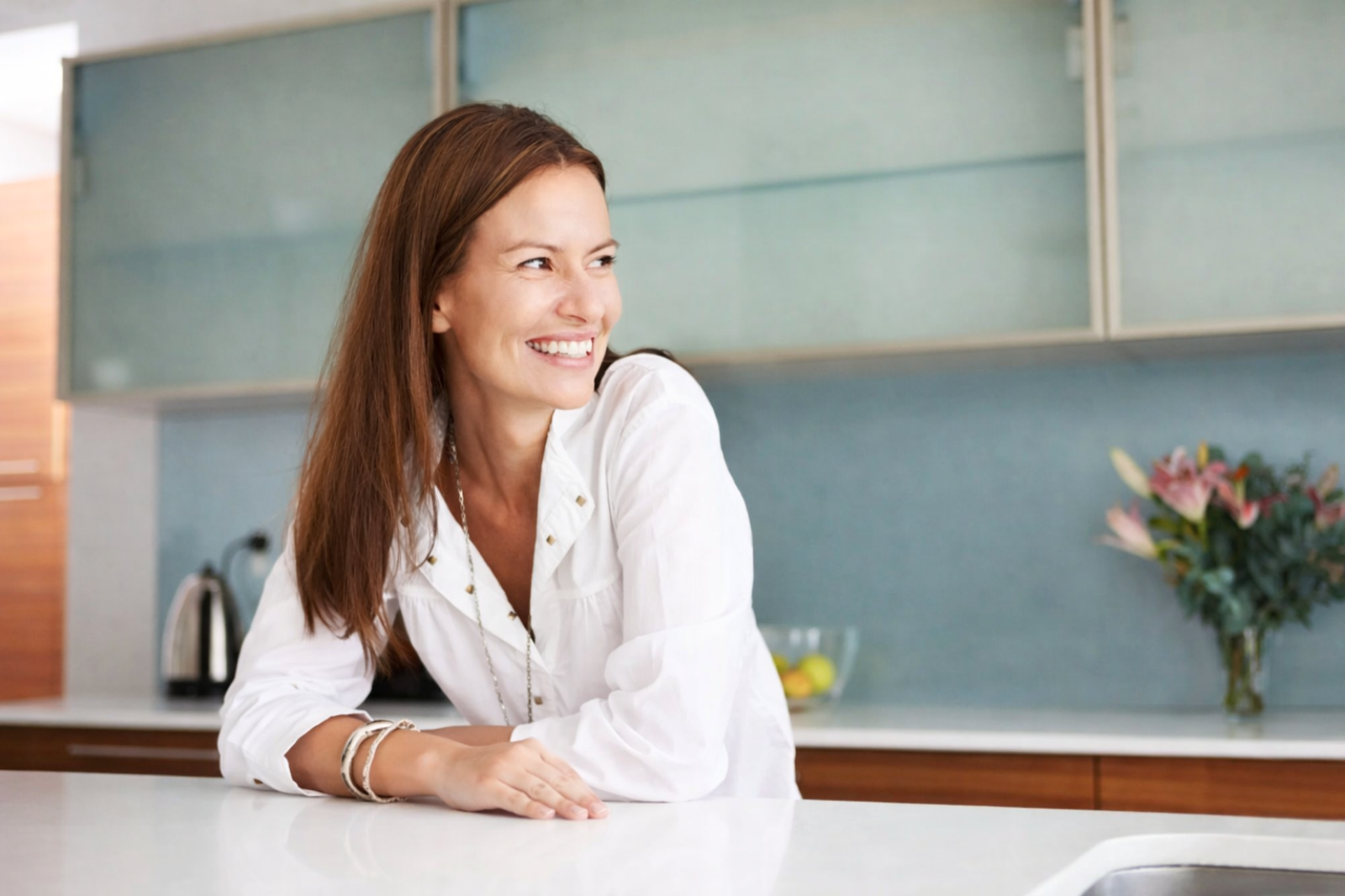 Smiling woman leaning on kitchen counter after whole person healthcare near me in Austin Texas with Dr Womack at Westlake Medical Arts