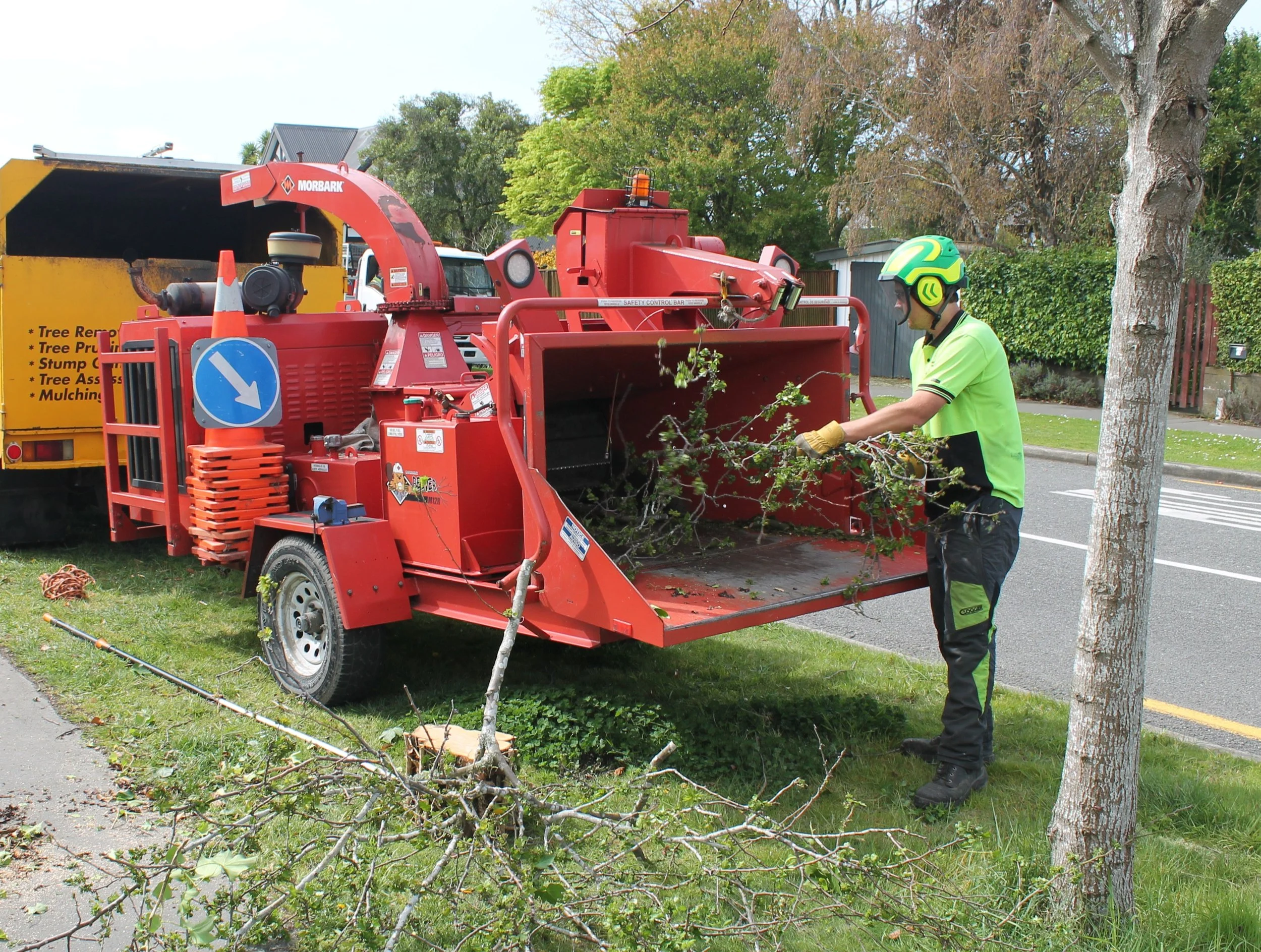 arborist feeding a wood chipper on a cloudy day in Christchurch