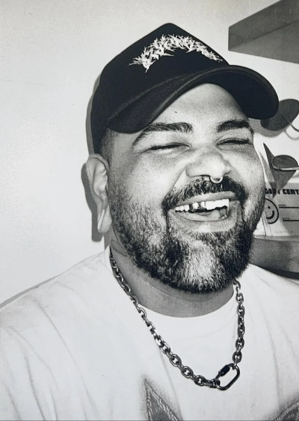 A man with a beard wearing a chain necklace and baseball cap 