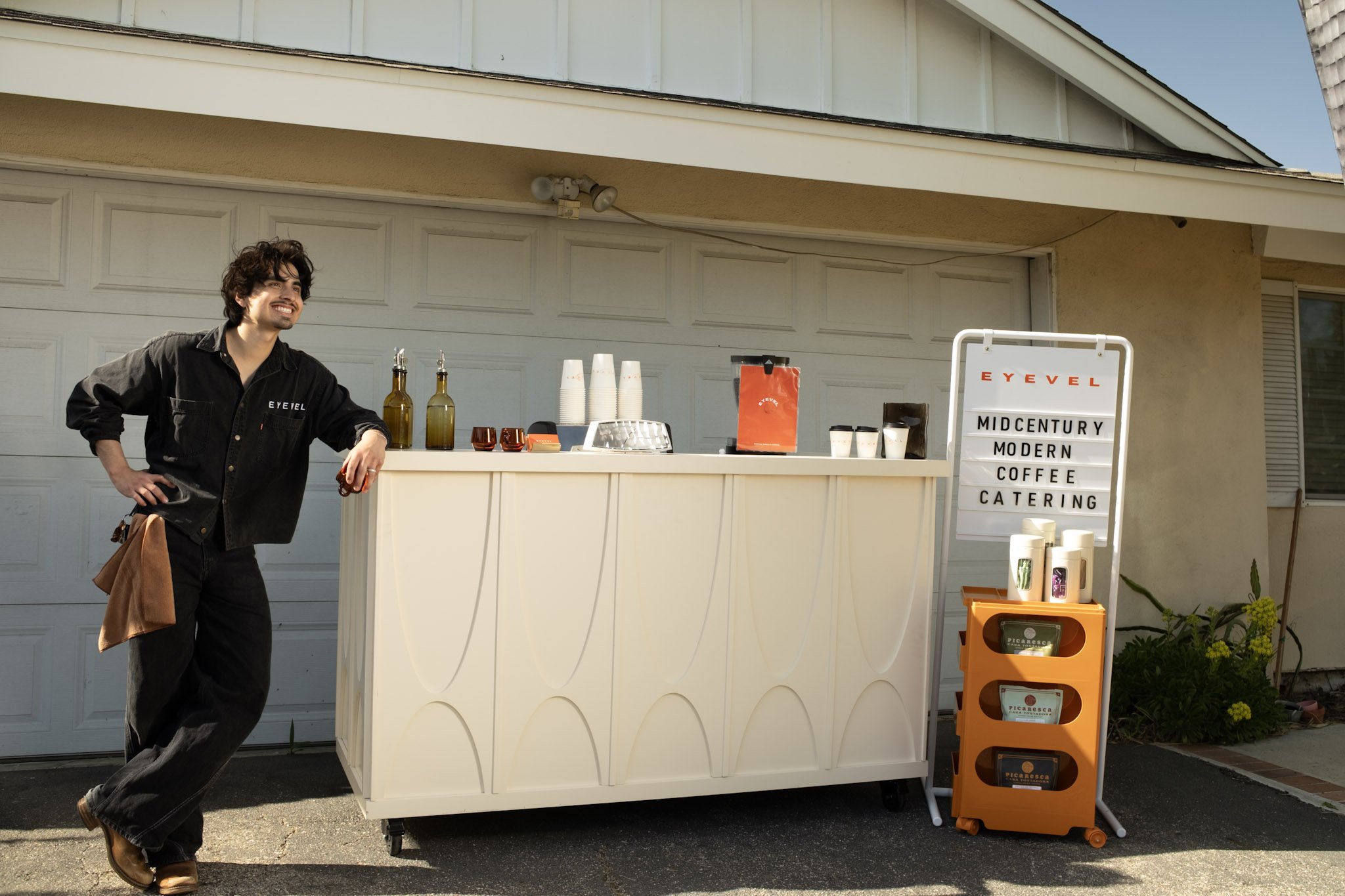 man smiling on right side of coffee cart 