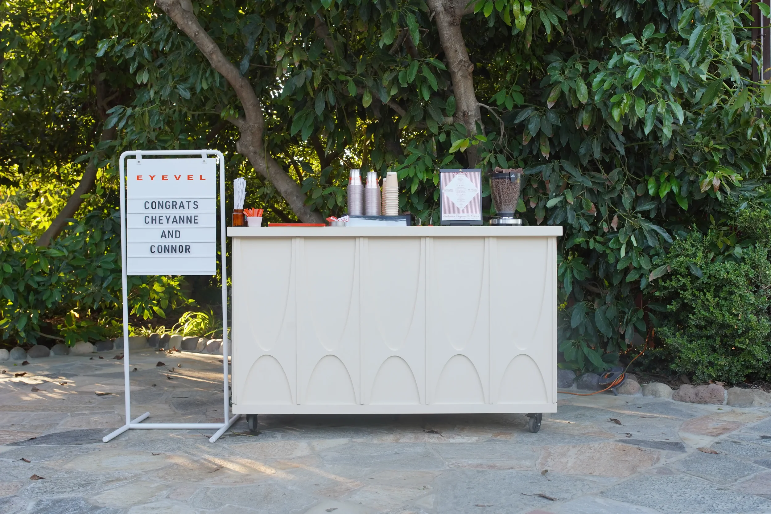 The coffee cart under the trees at a garden wedding