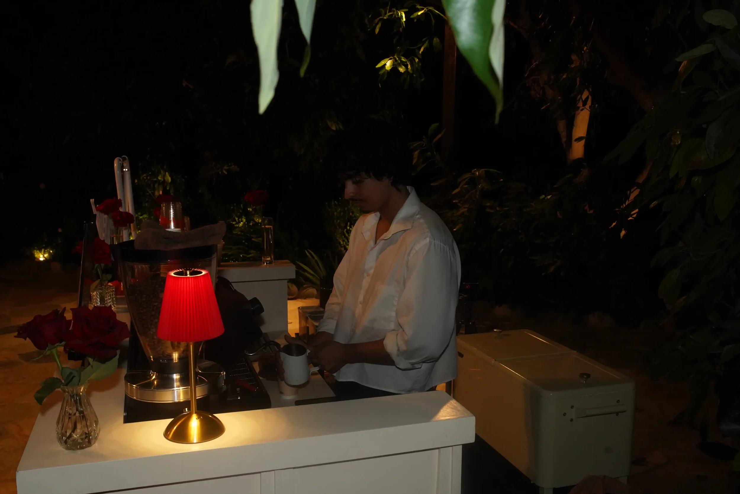 A barista working the cart by lamplight after dark