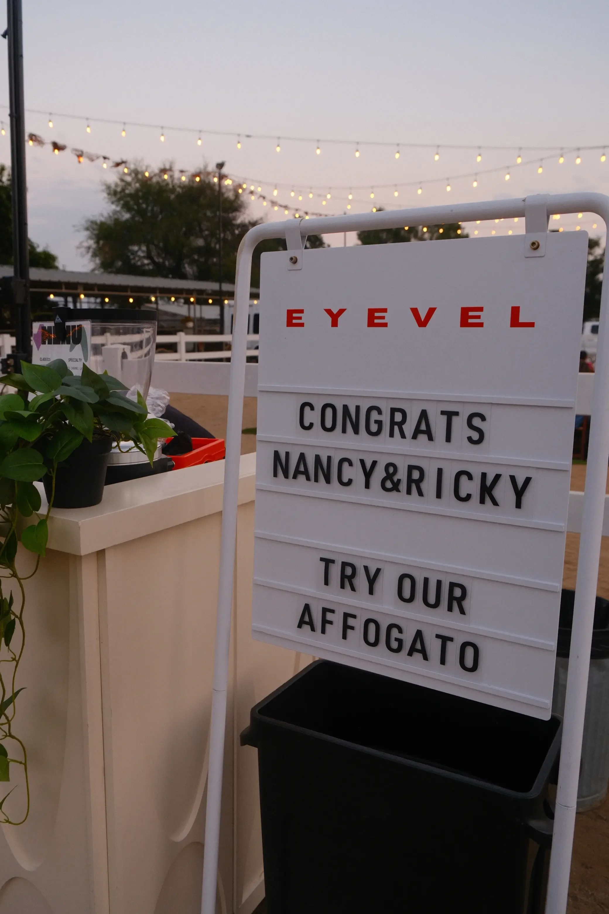 EYEVEL letterboard sign under string lights at dusk