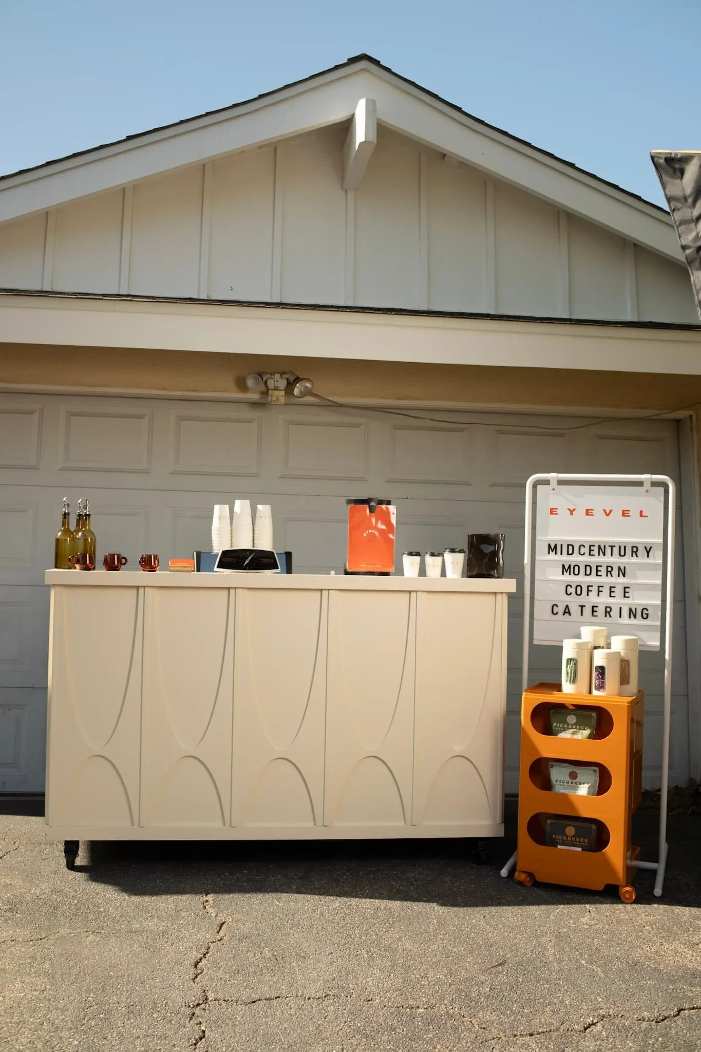 mobile coffee cart outside of garage with sign that says eyevel coffee catering
