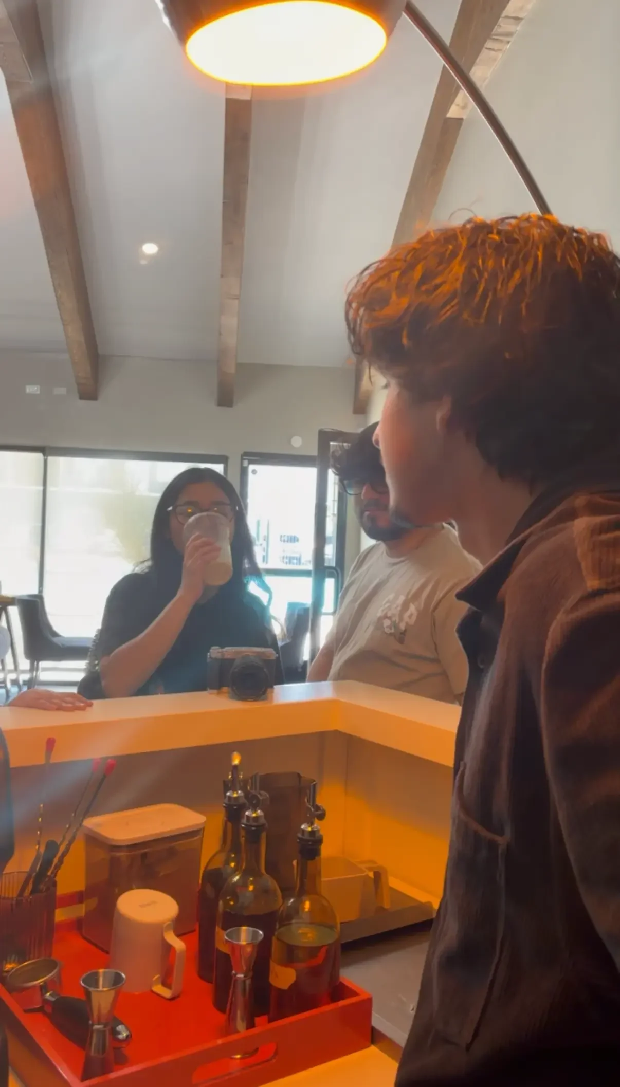 Customers drinking freshly made espresso drinks at a mobile coffee cart operated by a single barista.