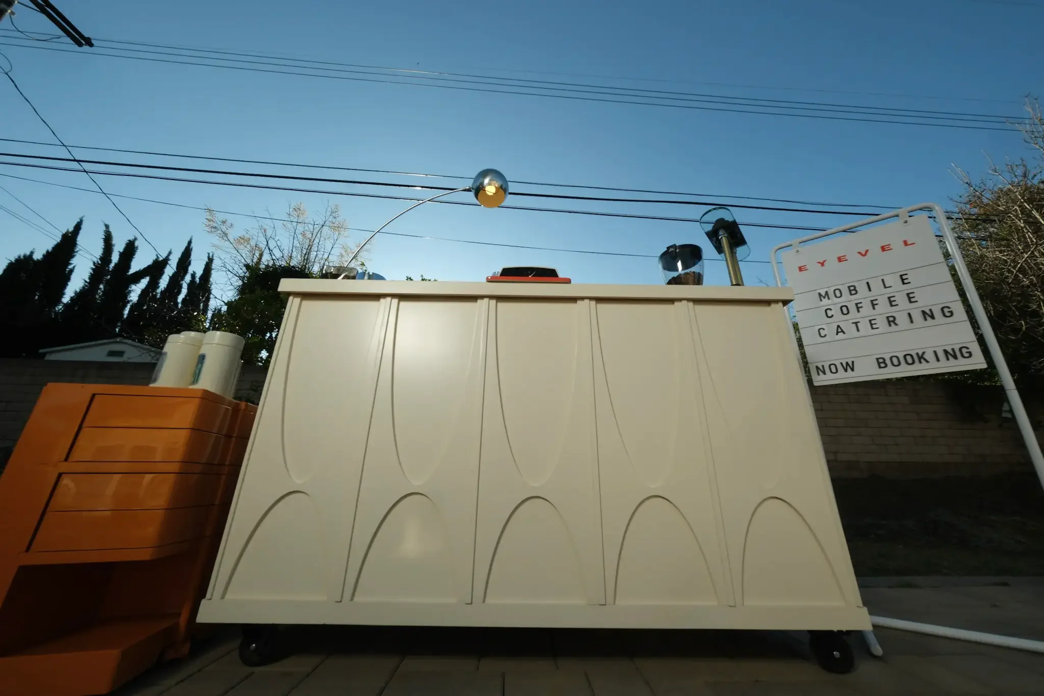 The cart outdoors beside its mobile coffee catering sign