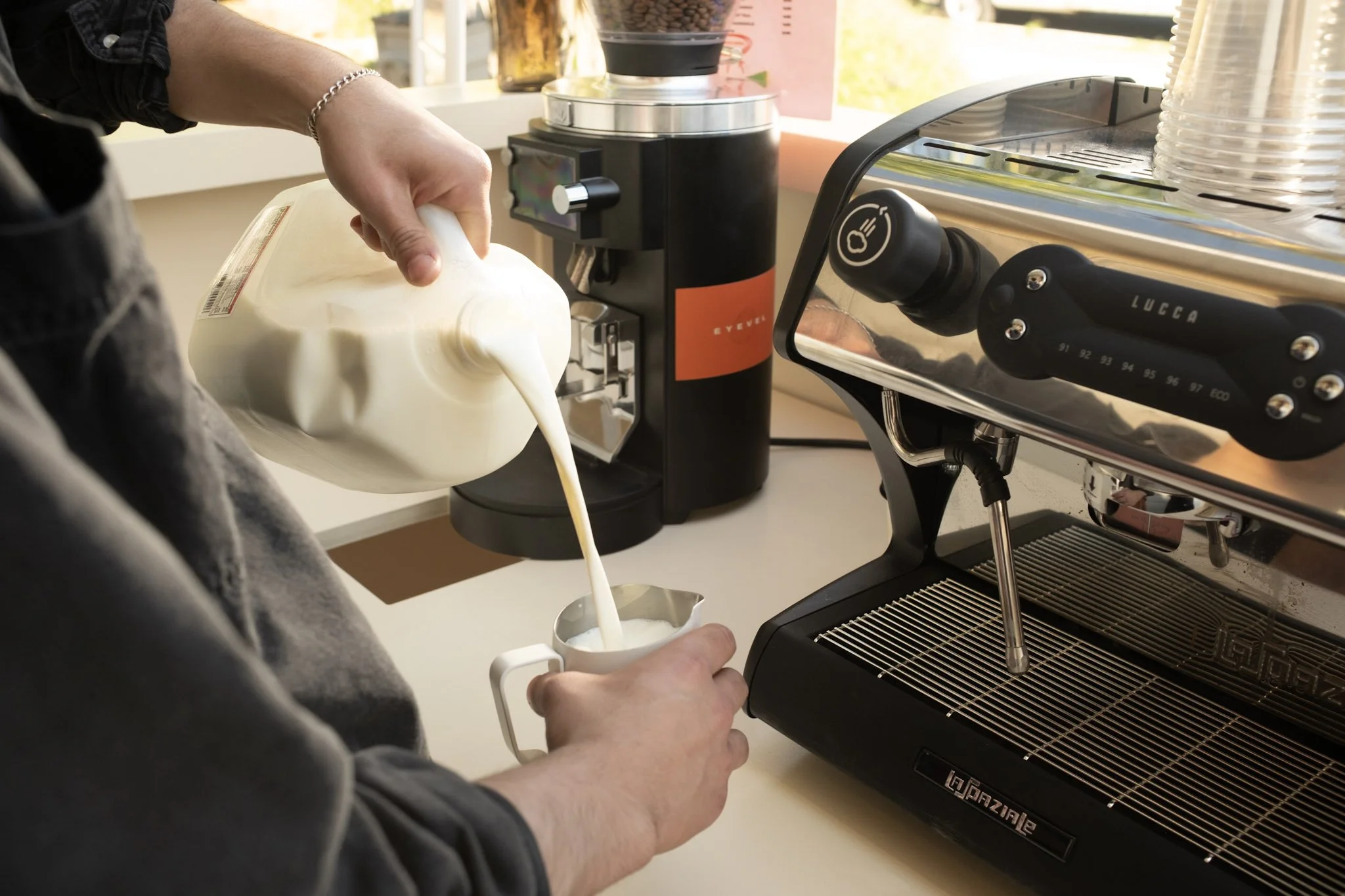 man pouring milk into milk pitcher standing behind coffee cart 