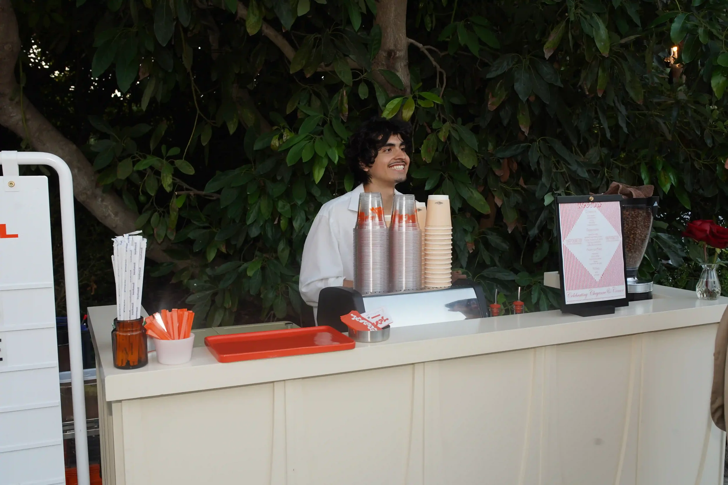 A smiling barista behind the Eyevel cart at dusk