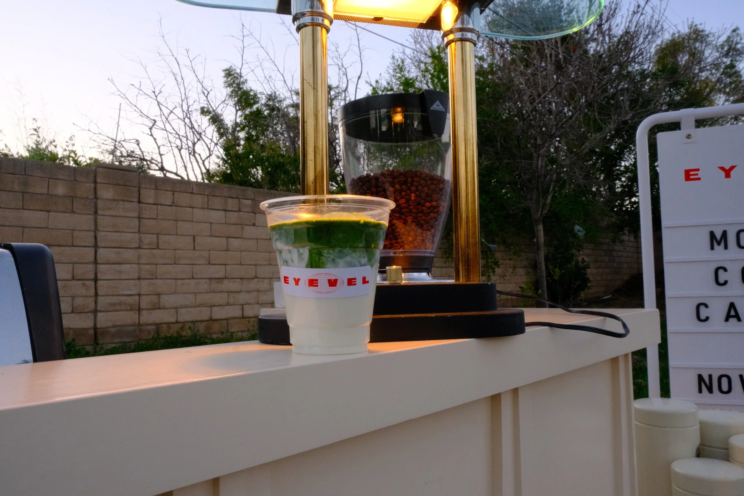 matcha latte with orange light above on counter of coffee cart