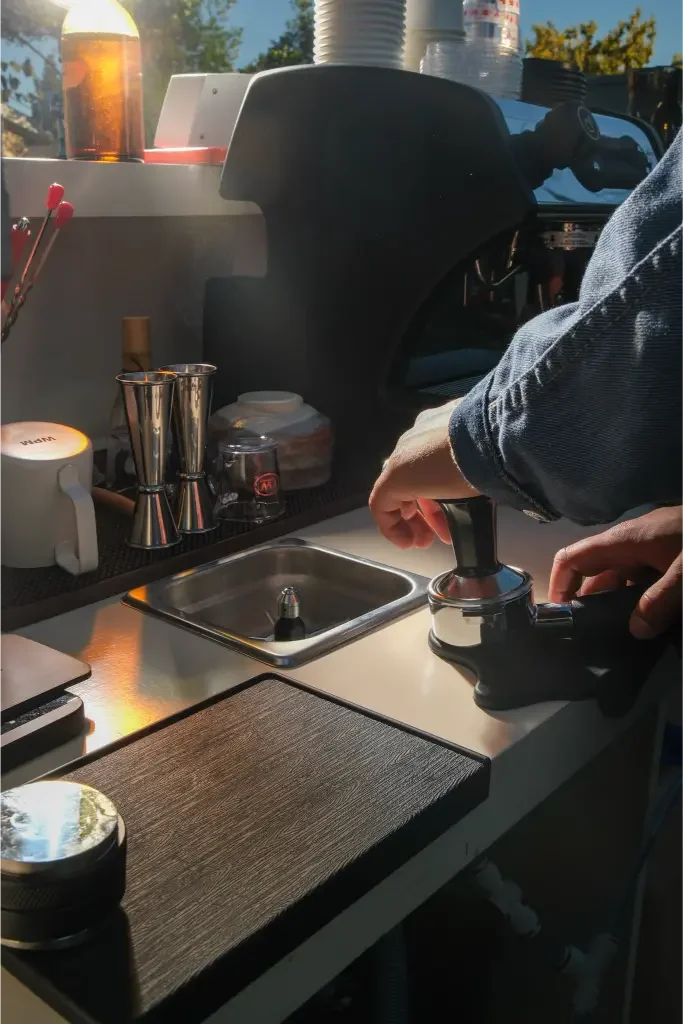 Tamping a fresh dose of coffee at the bar in warm evening light