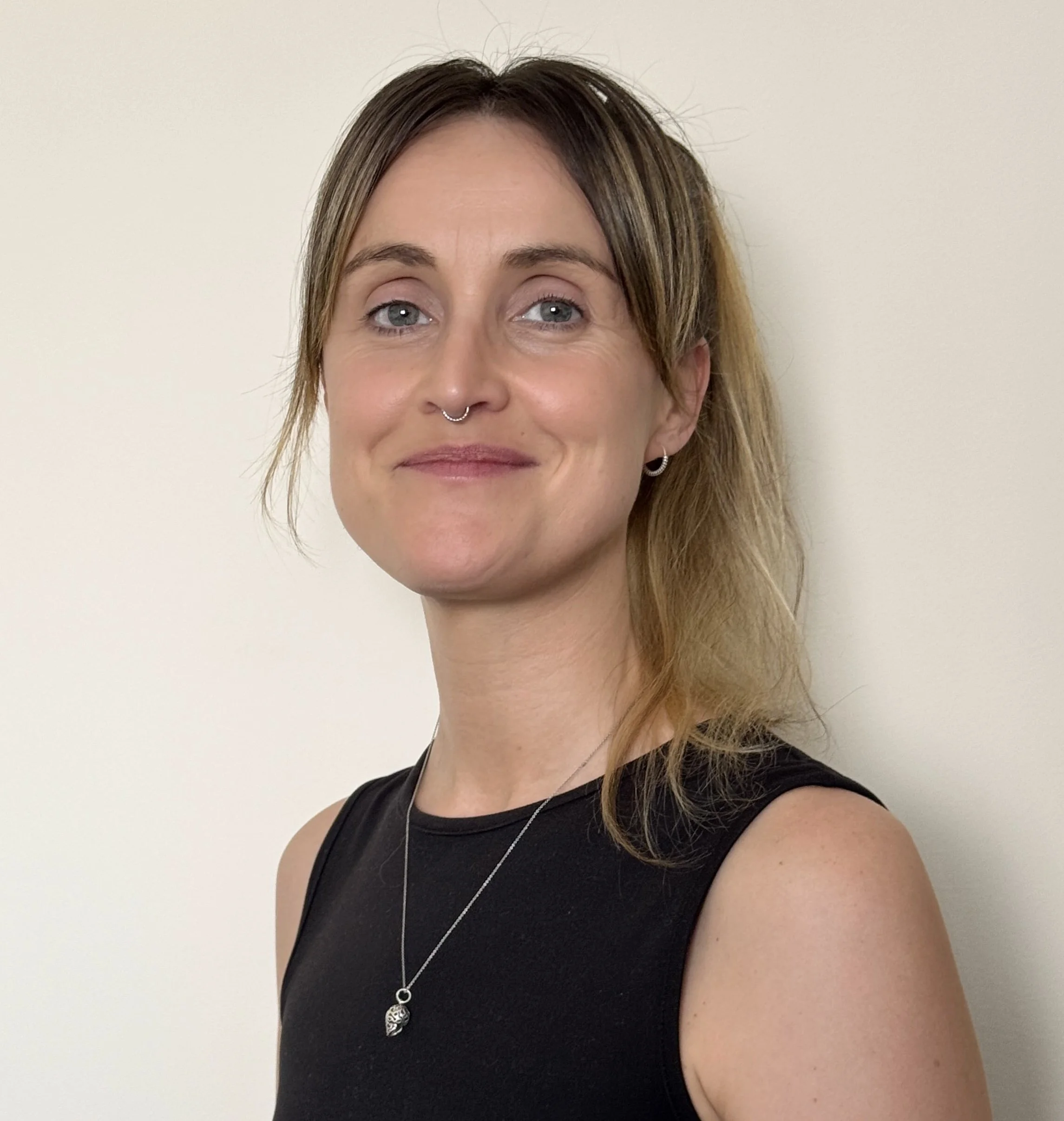 A smiley and beautiful Spanish women in a black top and with a necklace 