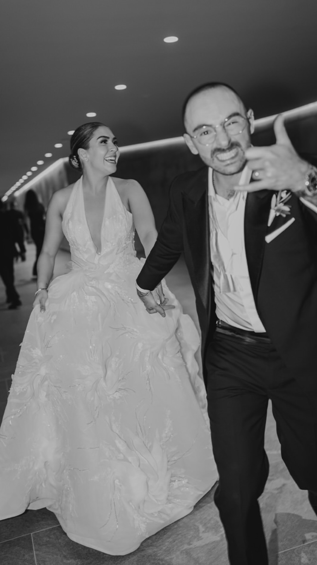 Una pareja de recién casados bailando, la mujer con vestido de novia y el hombre con traje, en un evento social.