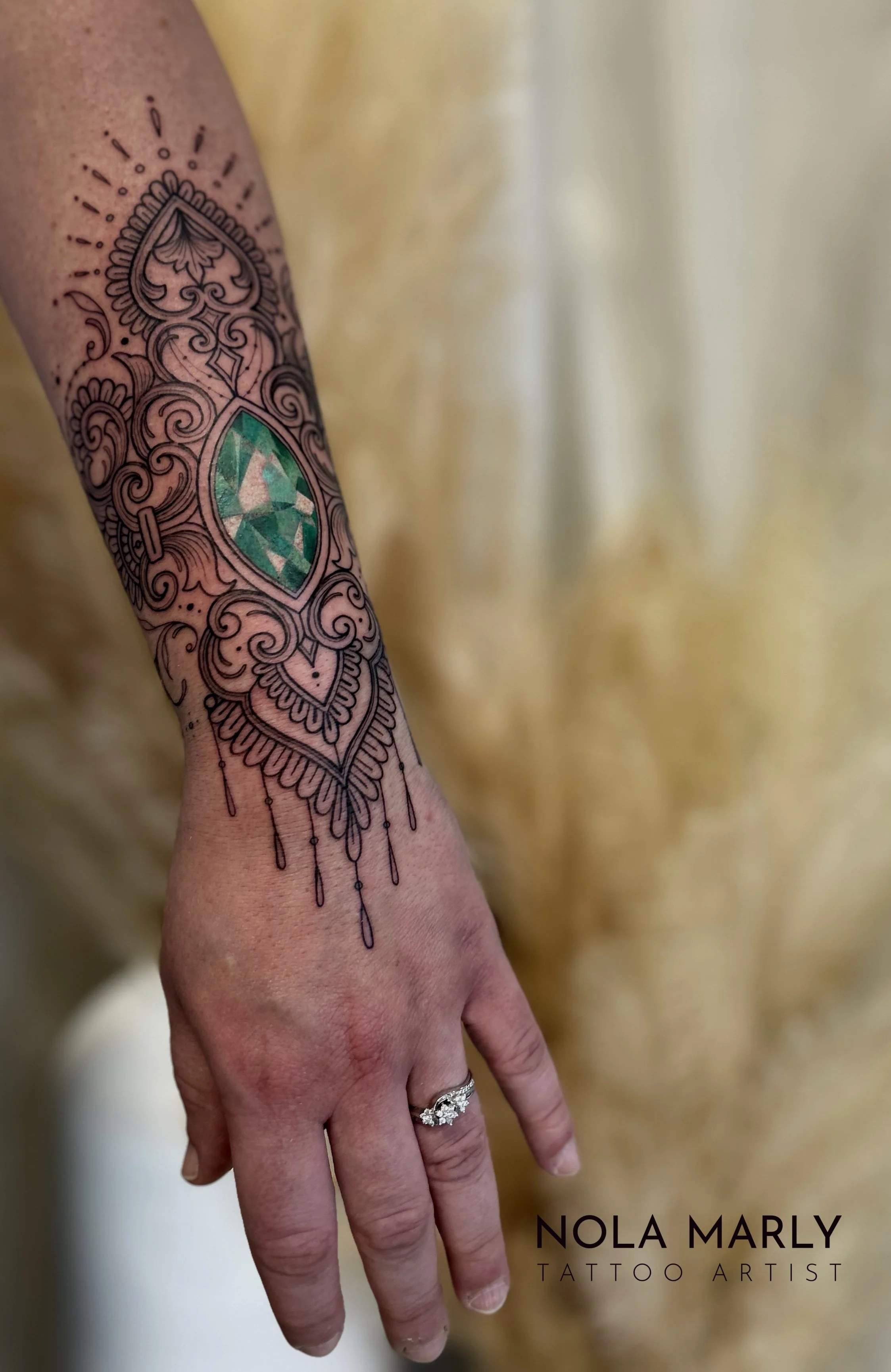 Tattoo avant-bras féminin avec bijoux diamant vert émeraude et ornemental détaillé et féminin
