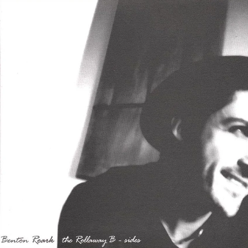 Black and white photo of a woman smiling, wearing a hat, with part of her face visible.