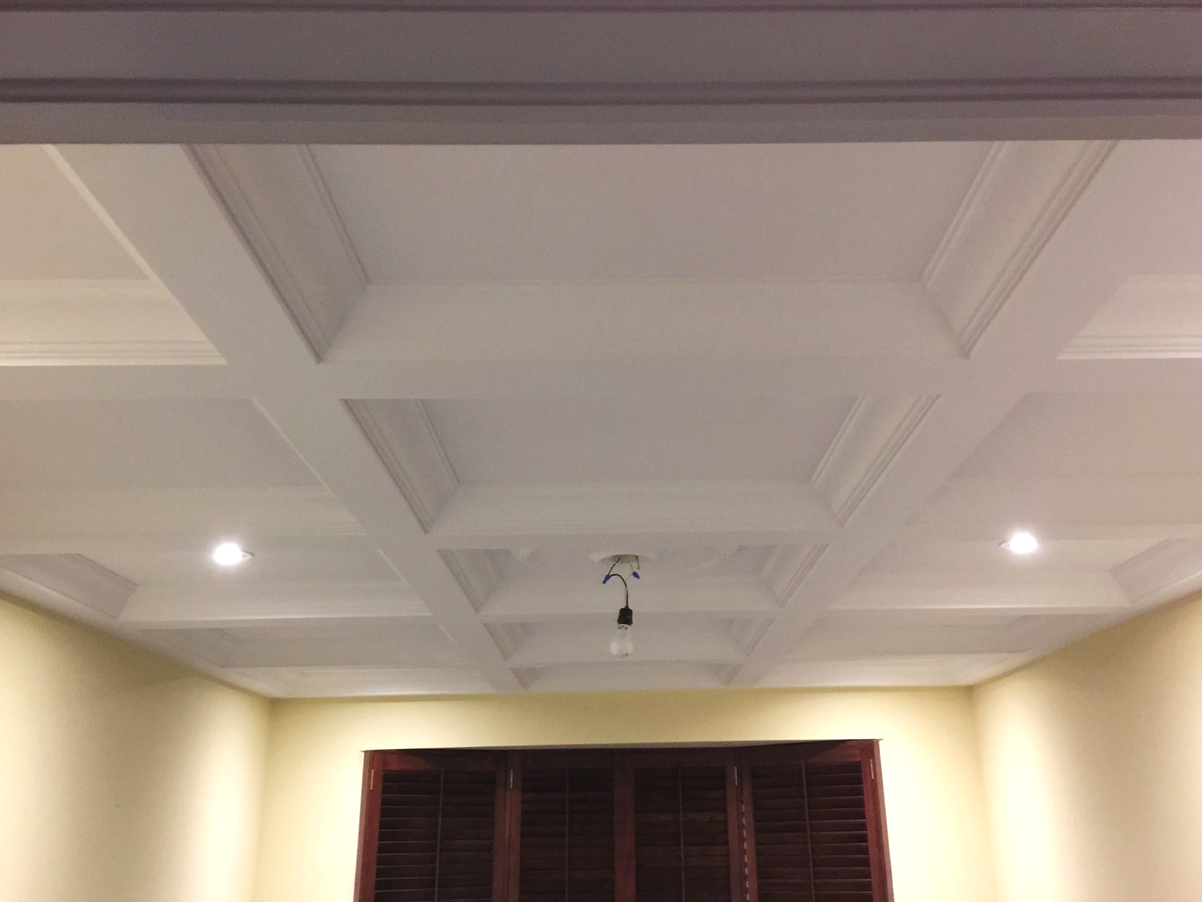 Ceiling with decorative molding, recessed lighting, and a hanging light fixture with exposed wiring.