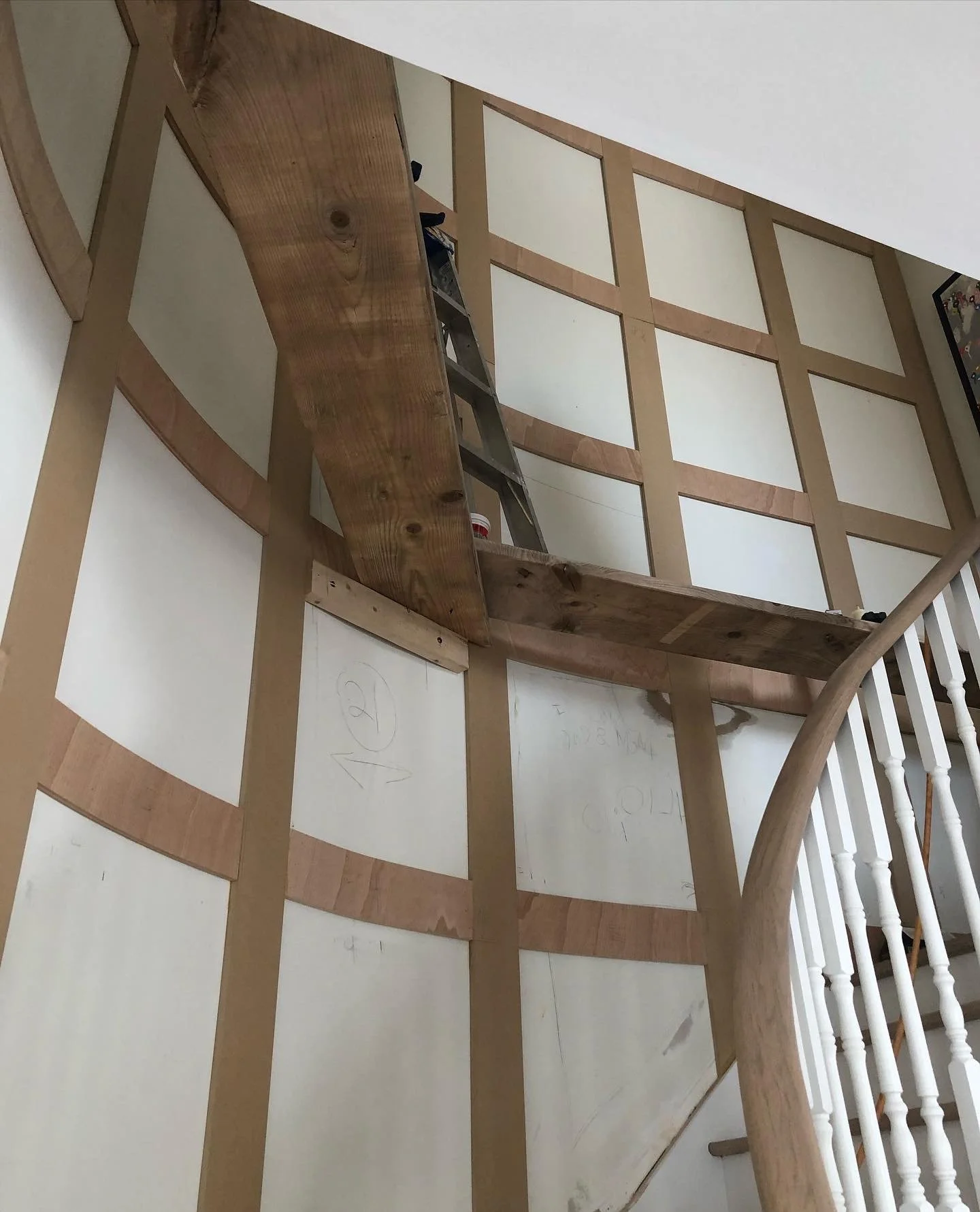 Interior of a house under construction with a wooden staircase and unfinished wall framing.