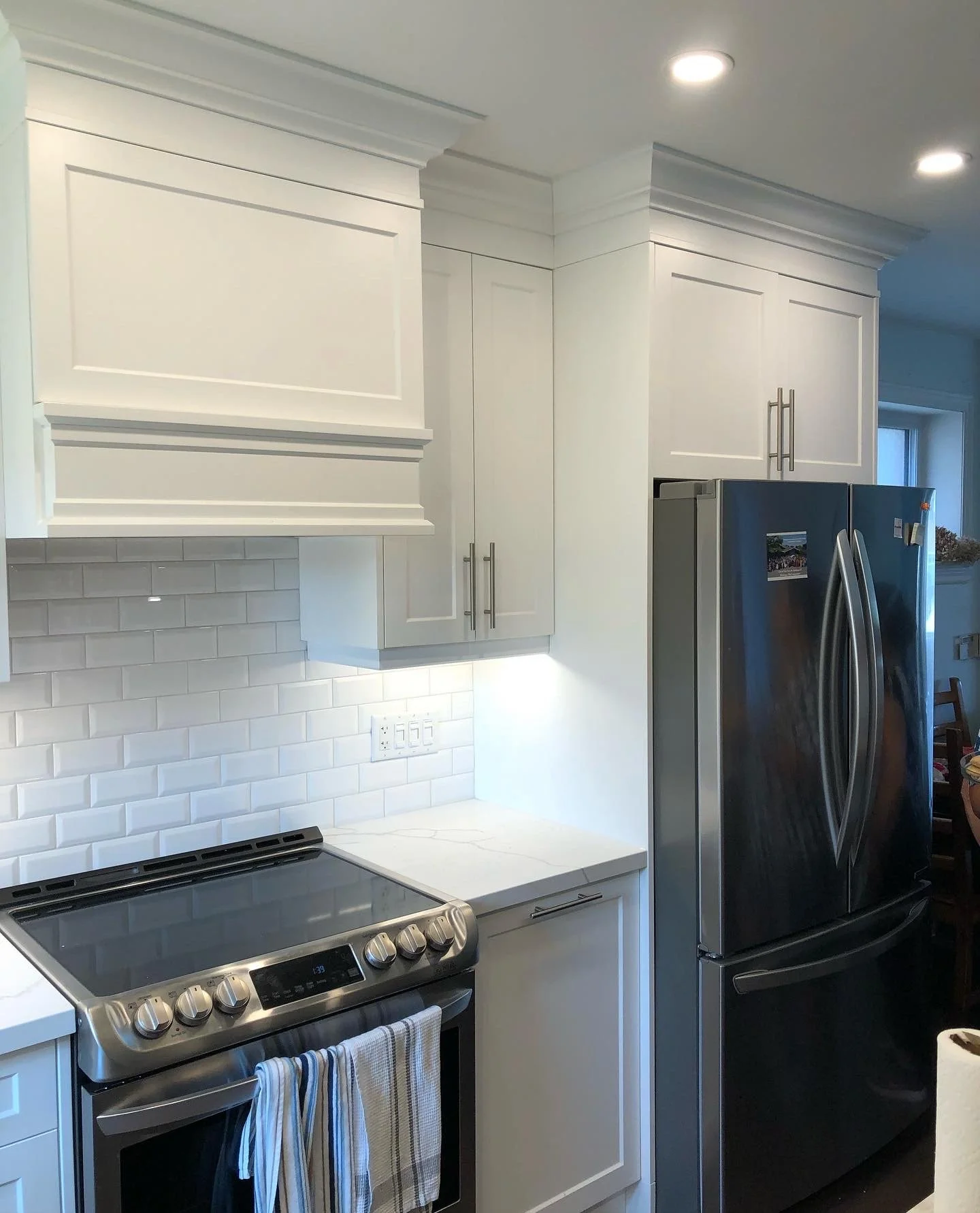 Modern kitchen with white cabinets, marble countertop, stainless steel oven, and black refrigerator.