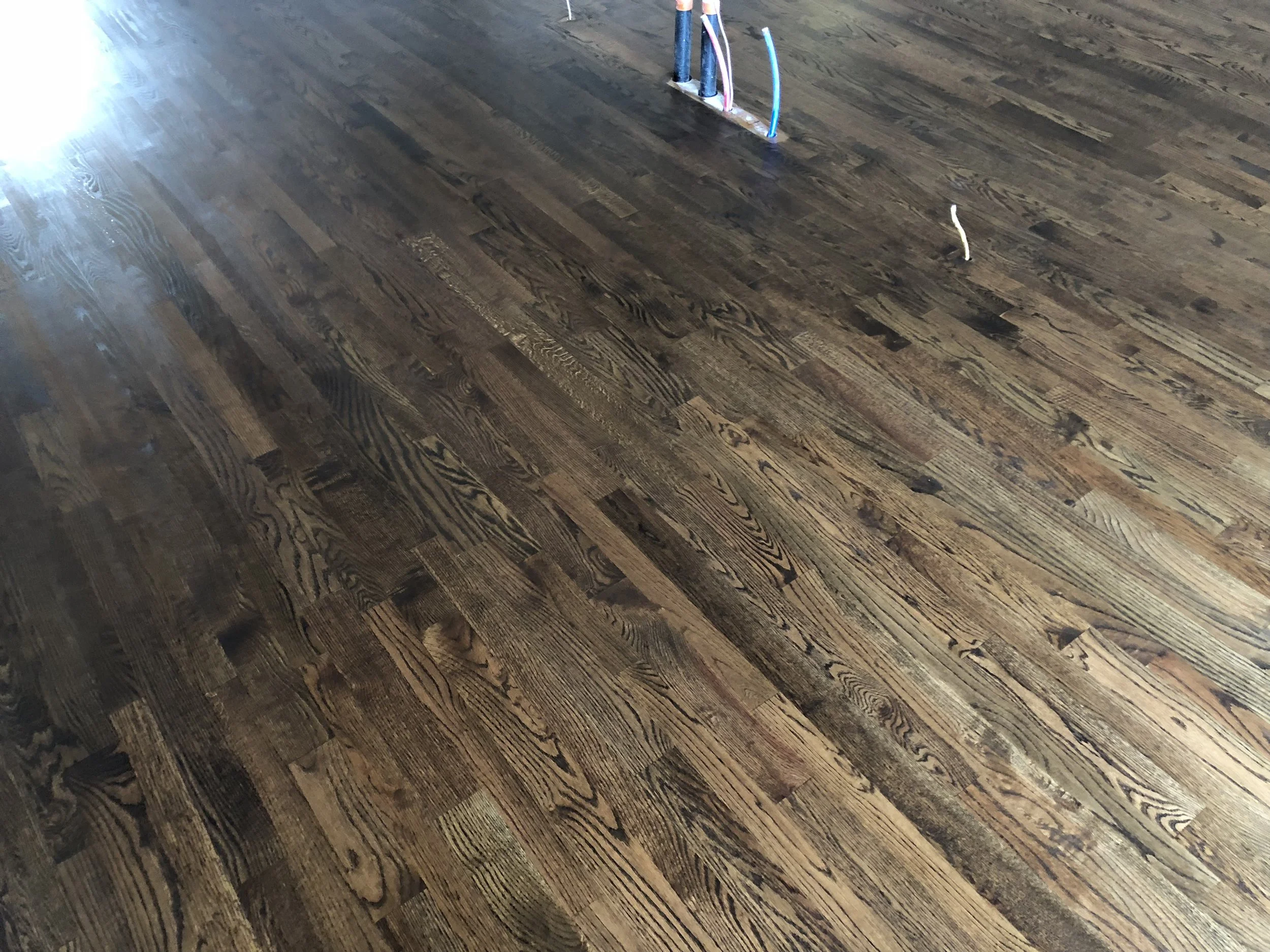 Freshly installed hardwood flooring in a room in Stayner with exposed electrical wiring.