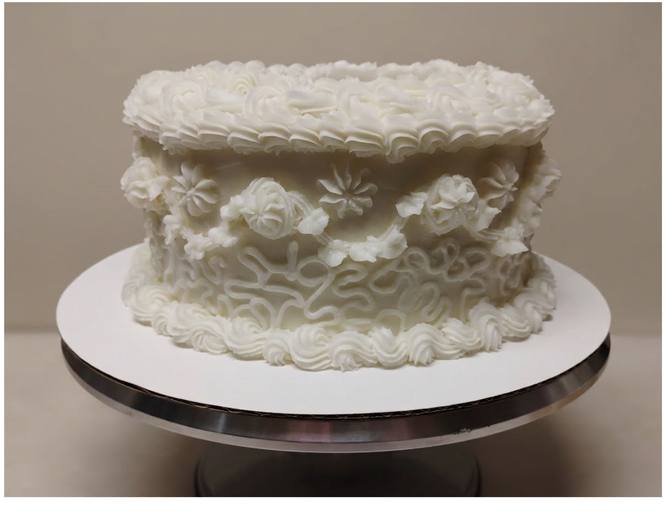 A one-tiered white cake decorated with piped icing roses and floral patterns on the sides, sitting on a silver cake stand.