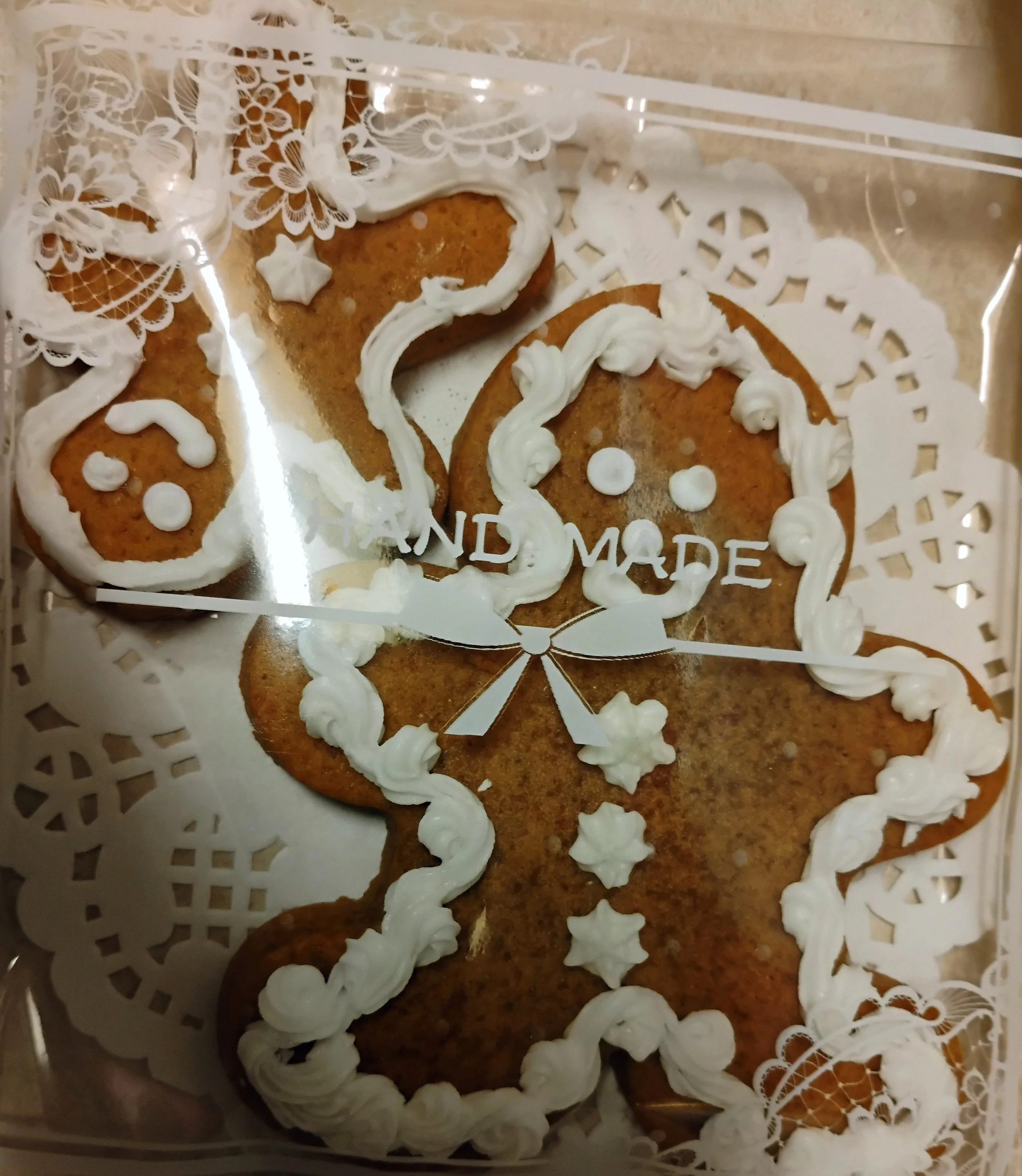 Cupcake decorated with green frosting resembling grass, topped with two marshmallow ghosts with large googly eyes, and small orange pumpkins and black candies for Halloween decoration.