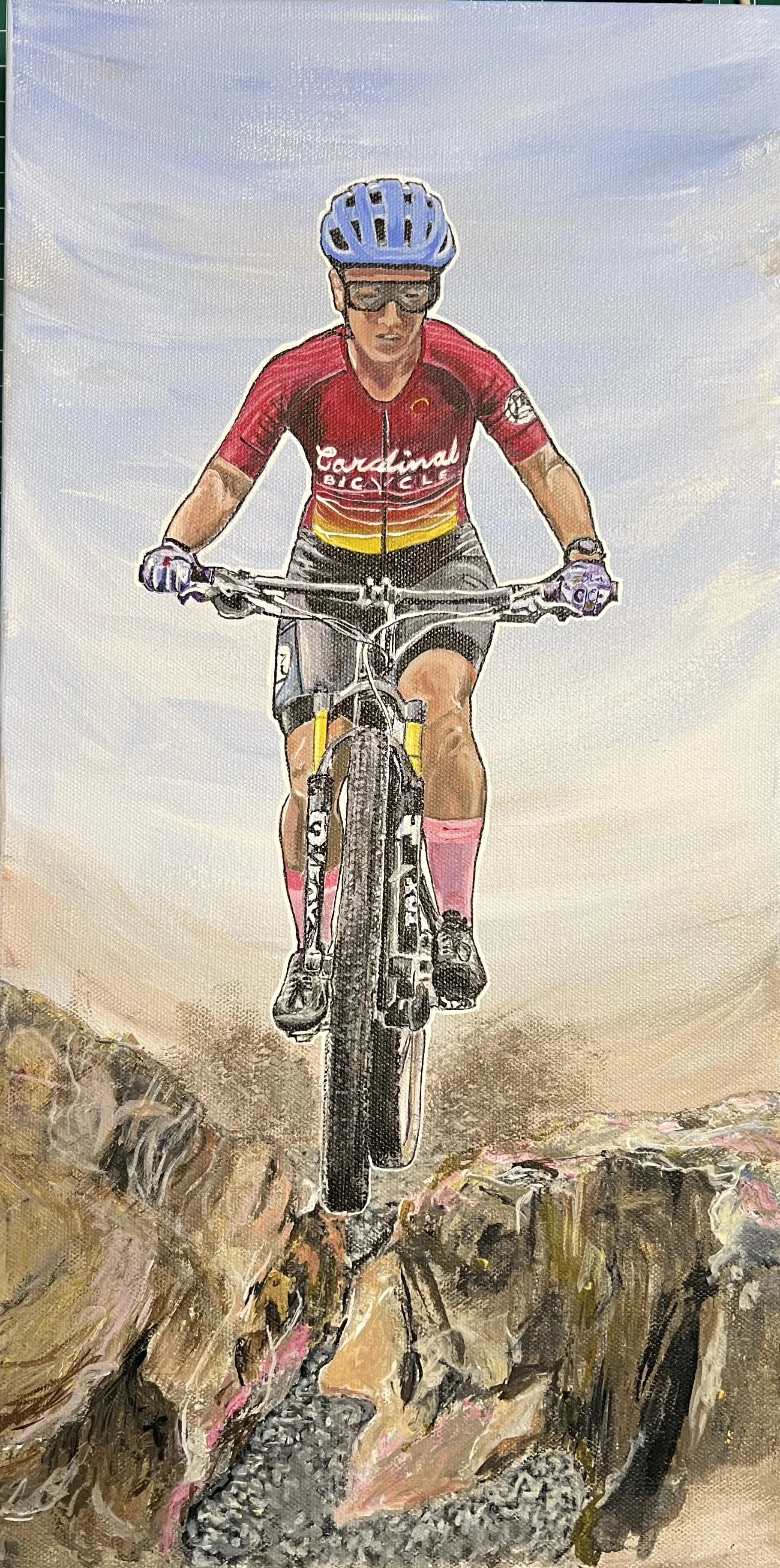 A woman “takes flight” through a narrow crevice in the rocks on her mountain bike.